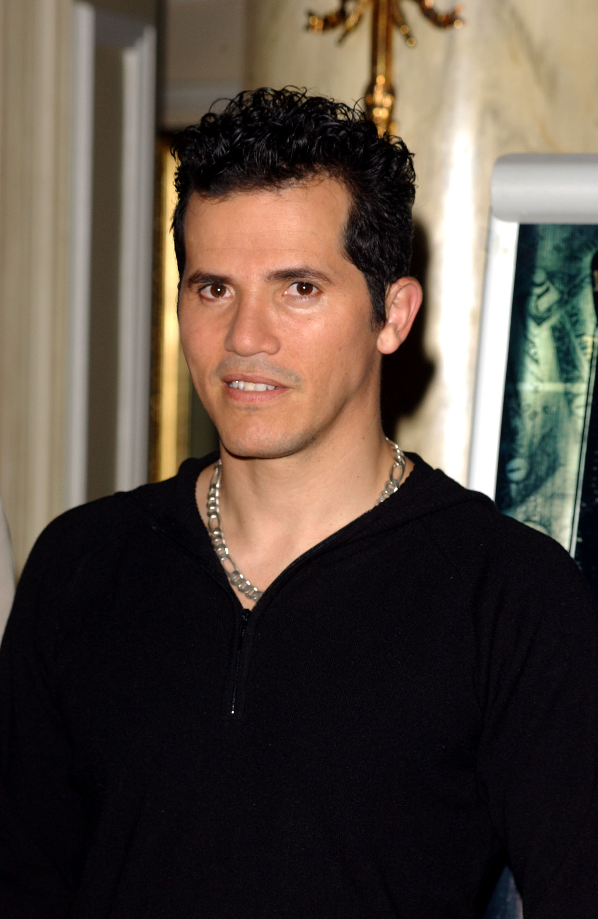 Actor John Leguizamo wearing a black zip-up top and silver chain necklace at a hotel event in Madrid, 2003.