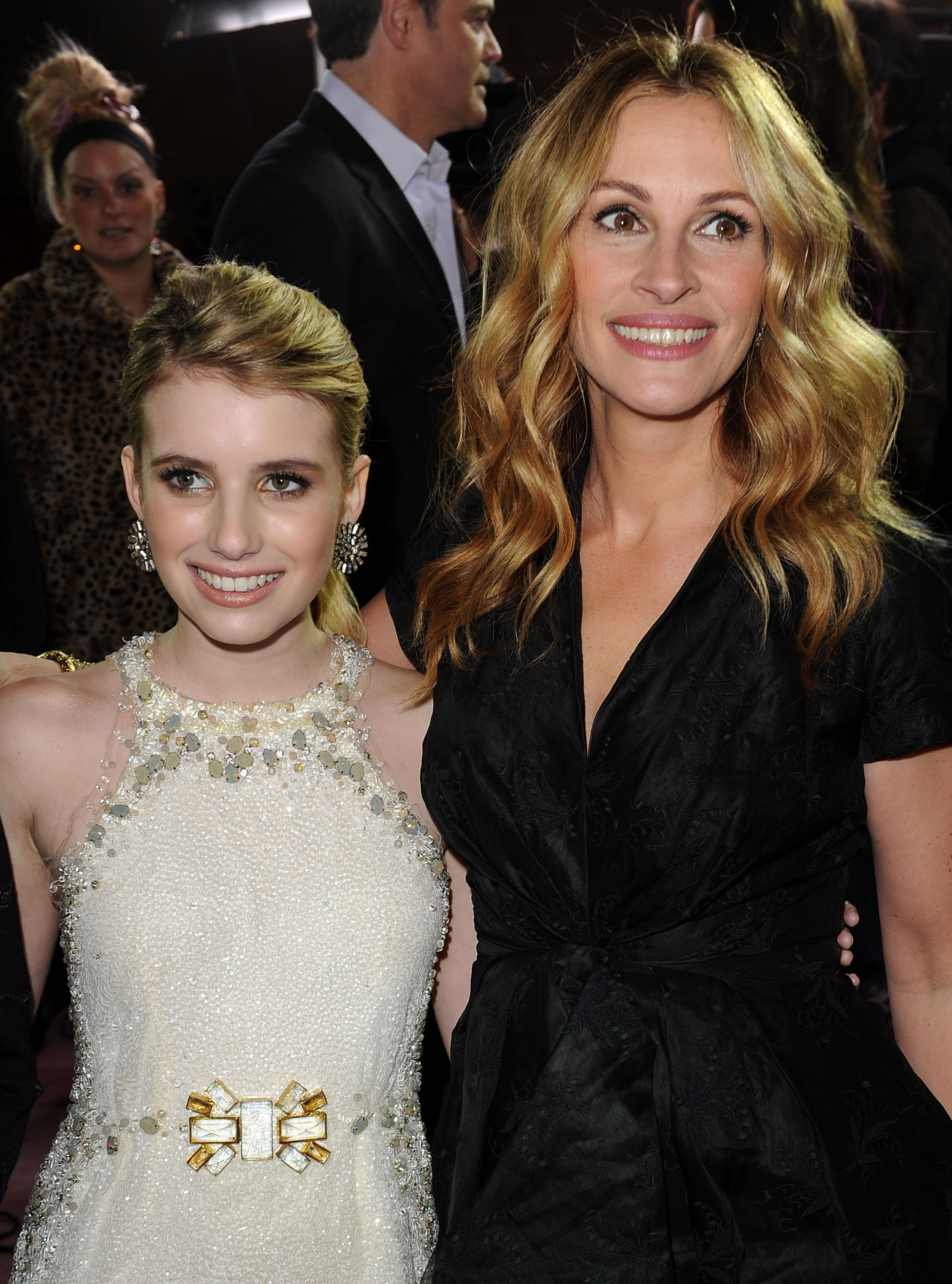 Emma Roberts in a white embellished gown and Julia Roberts in a black wrap dress pose together at a movie premiere.