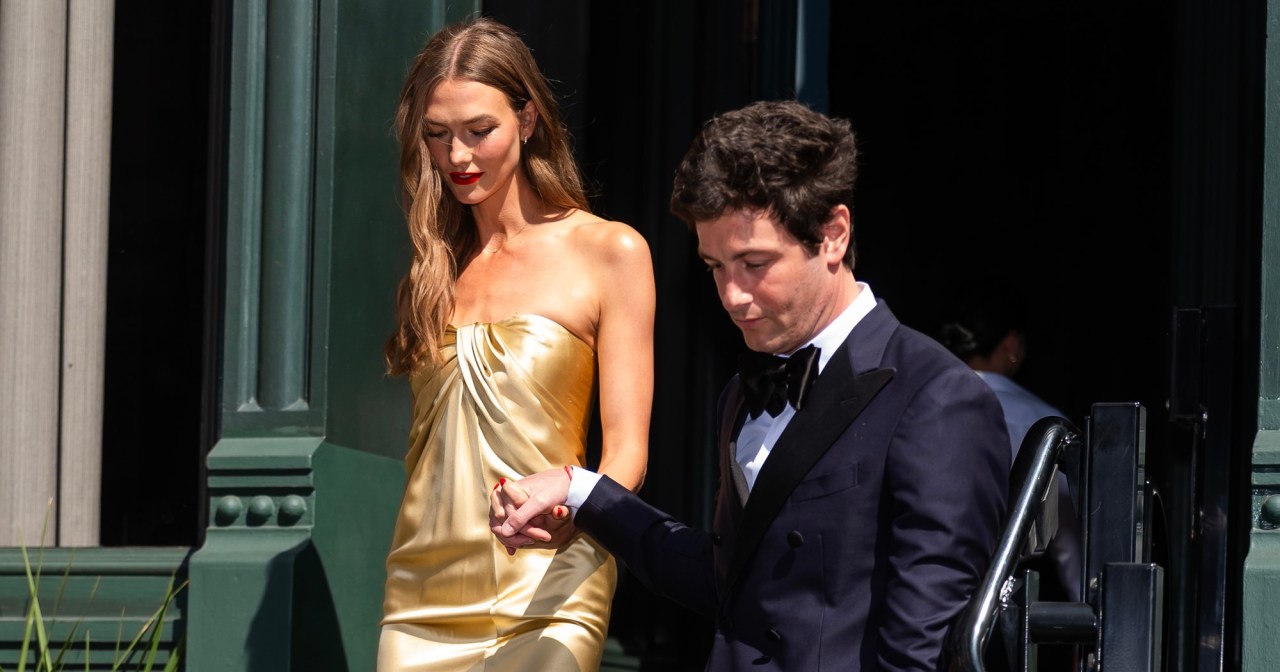 Karlie Kloss in a gold strapless satin gown and Joshua Kushner in a navy tuxedo walking down steps in SoHo, New York City.