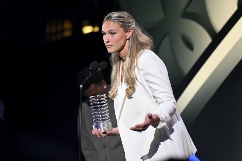 Kylie Kelce in a white blazer holding a silver trophy at a podium during the 30th Annual Webby Awards.