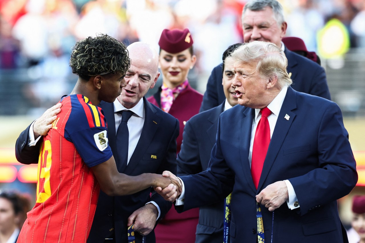 Lamine Yamal shaking hands with Donald Trump while Gianni Infantino stands between them with an arm around the player at the FIFA World Cup ceremony.