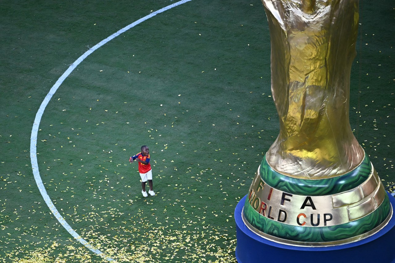 Keyne, Lamine Yamal's brother, gesturing next to a giant replica of the FIFA World Cup trophy after Spain's 2026 final win