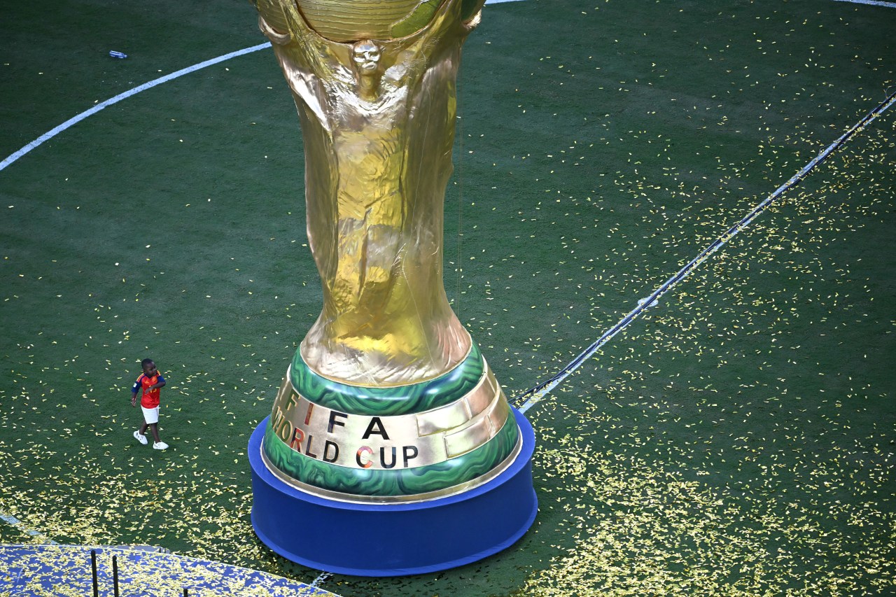 Lamine Yamal's brother Keyne walking toward a giant replica of the FIFA World Cup trophy at the trophy ceremony in East Rutherford, NJ