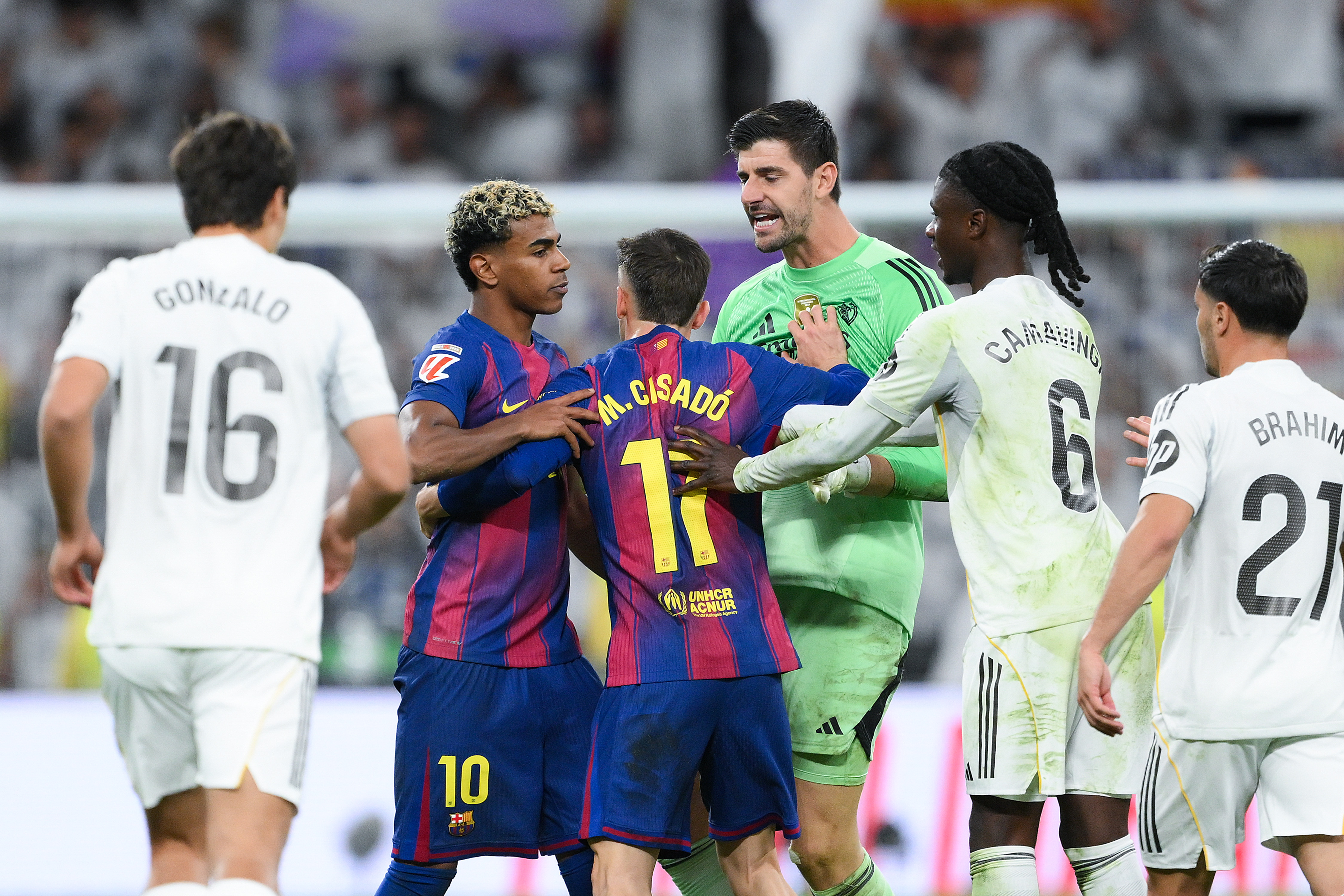 Click to open the image gallery Lamine Yamal restrained by a Barcelona teammate during a clash with Real Madrid players on the pitch at the Santiago Bernabéu
