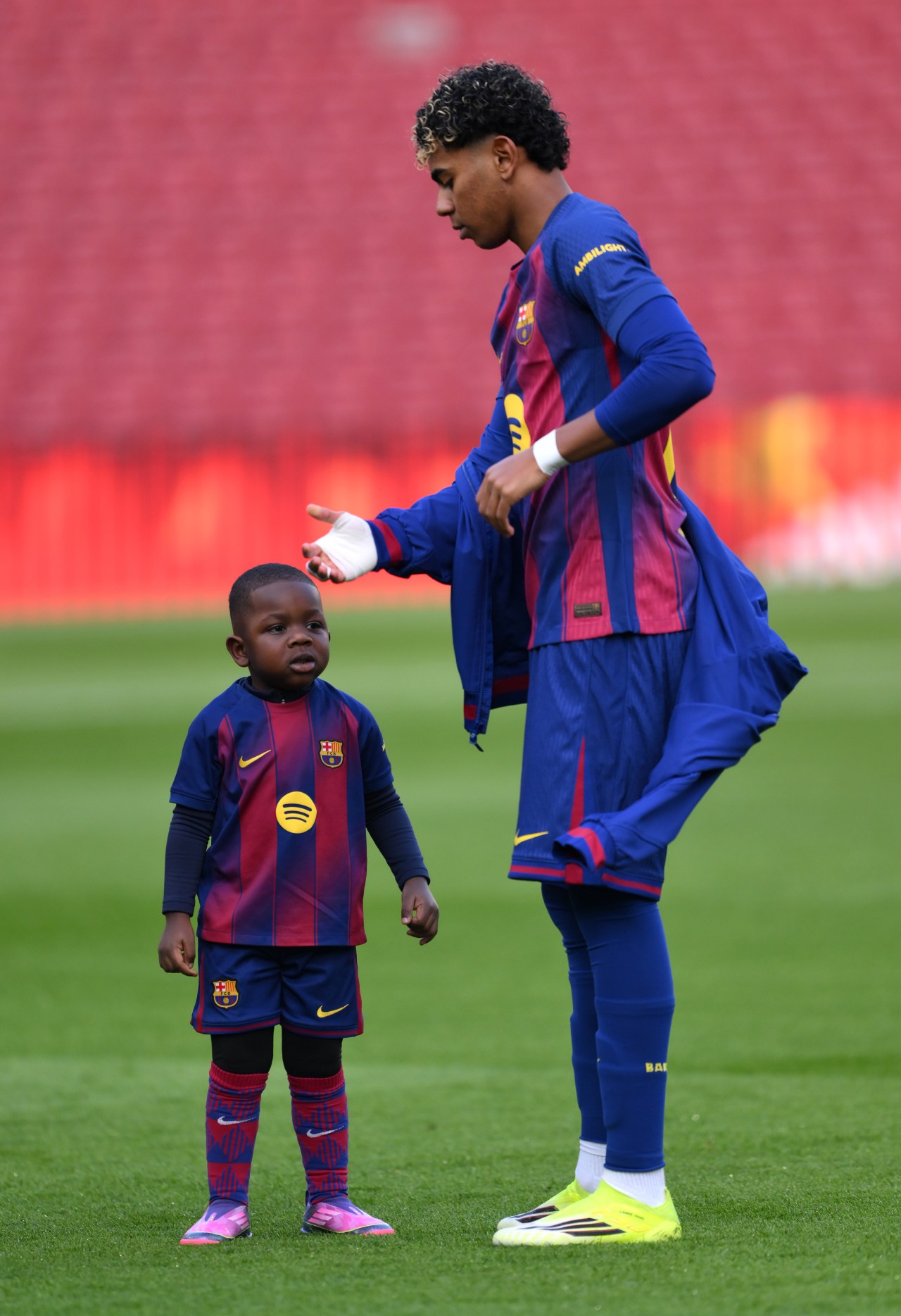 Lamine Yamal crouching on the pitch with his young half brother Keyne at Spotify Camp Nou