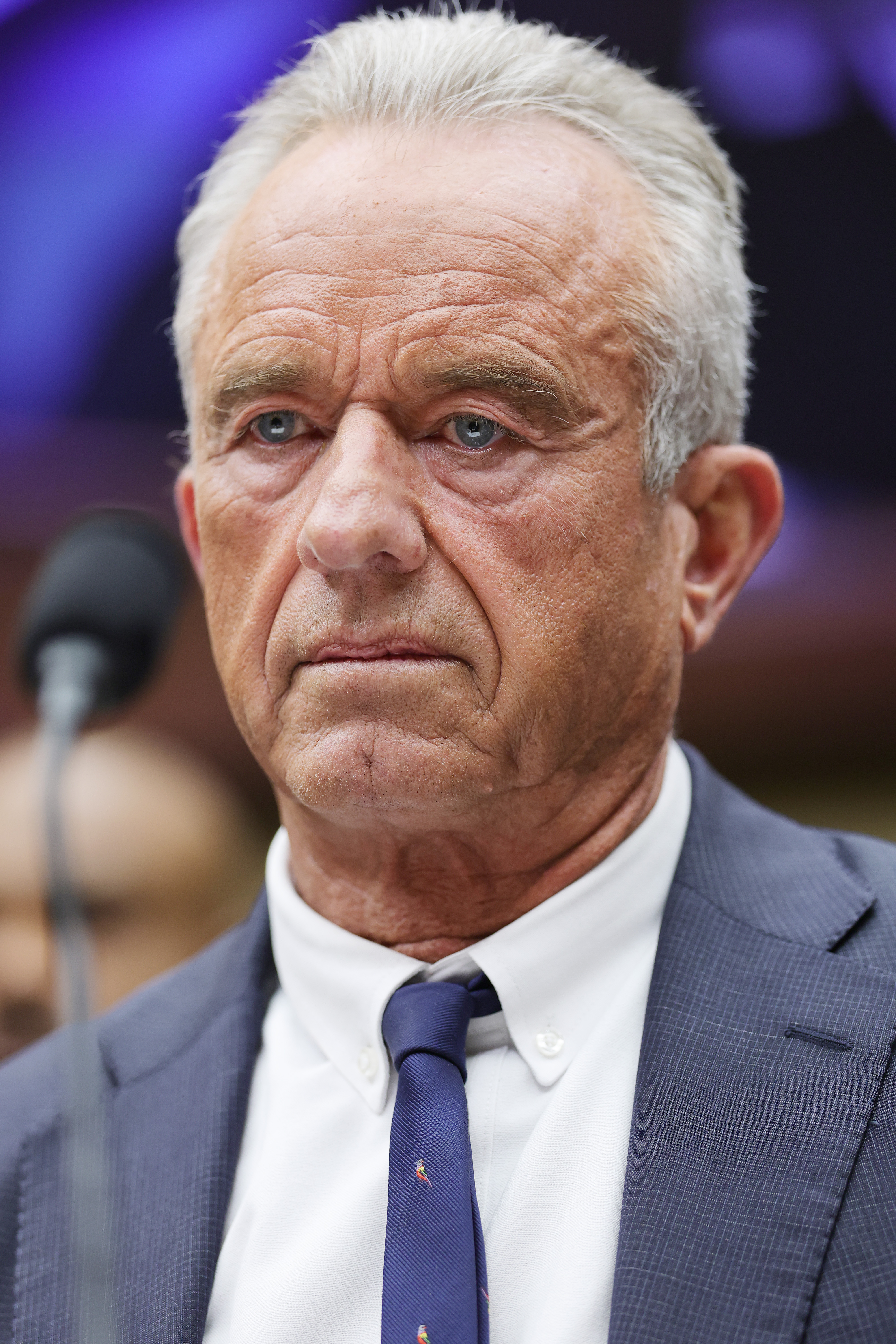 Robert F. Kennedy Jr. in a blue suit and navy tie, looking serious at a congressional hearing.
