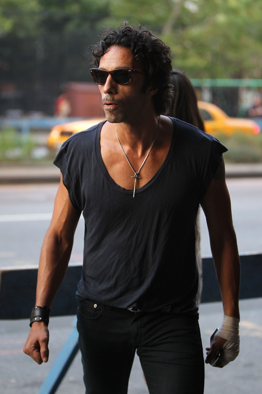 Carlos Leon wearing a black scoop-neck T-shirt and sunglasses walking on a New York City street.