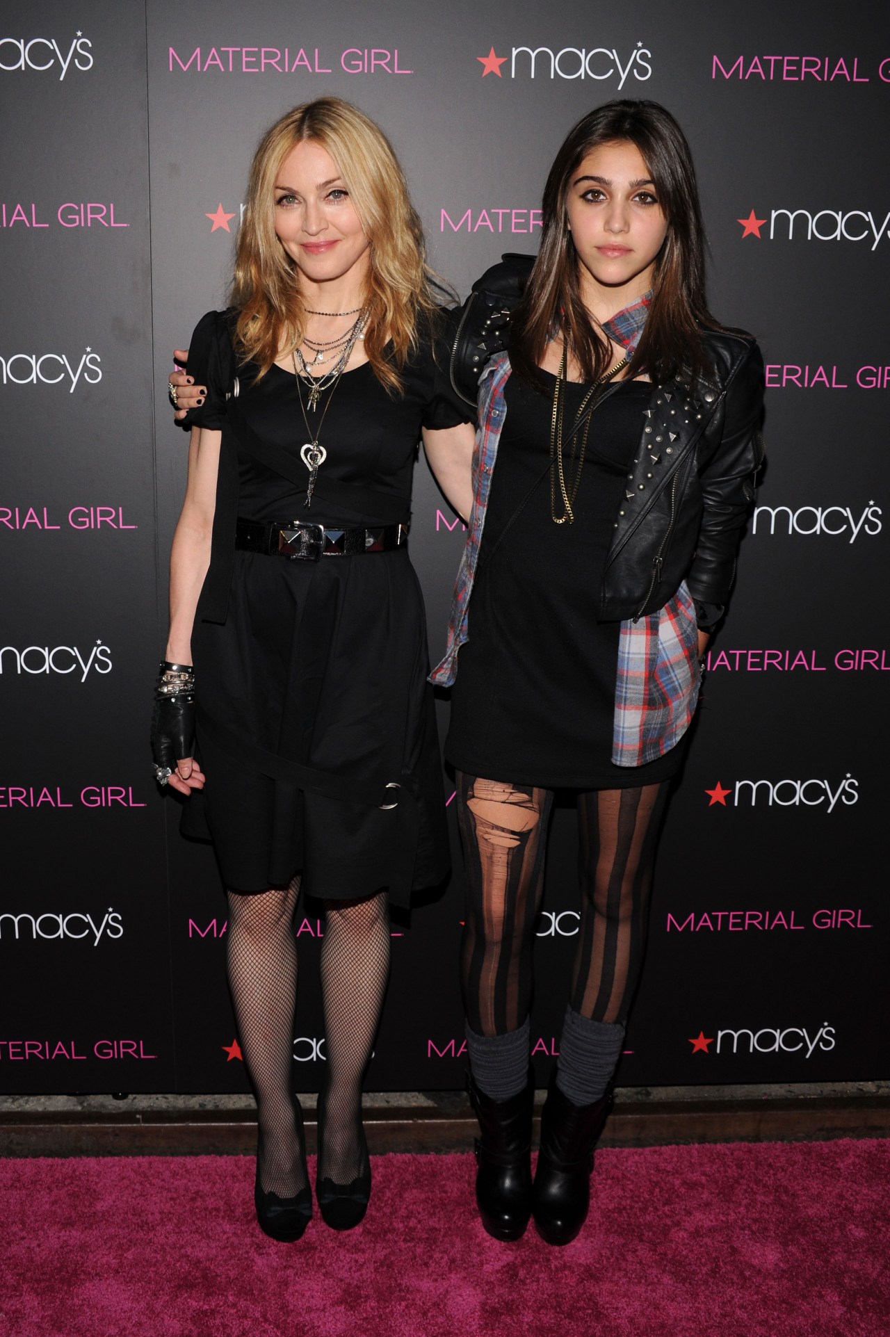 Madonna and Lourdes Leon both dressed in black standing together at the Material Girl collection launch in front of a Macy's backdrop.