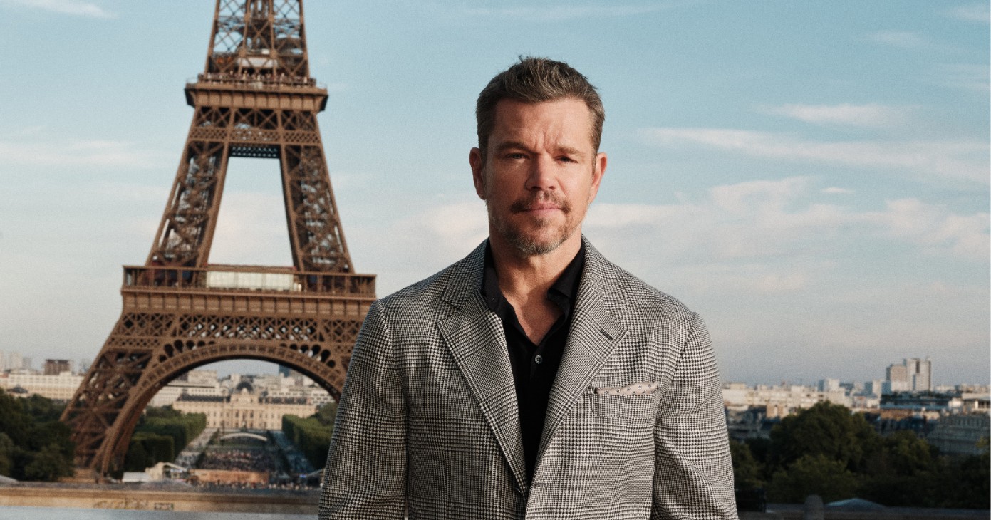 Man in a grey plaid suit standing at Trocadéro Square in Paris with the Eiffel Tower in the background