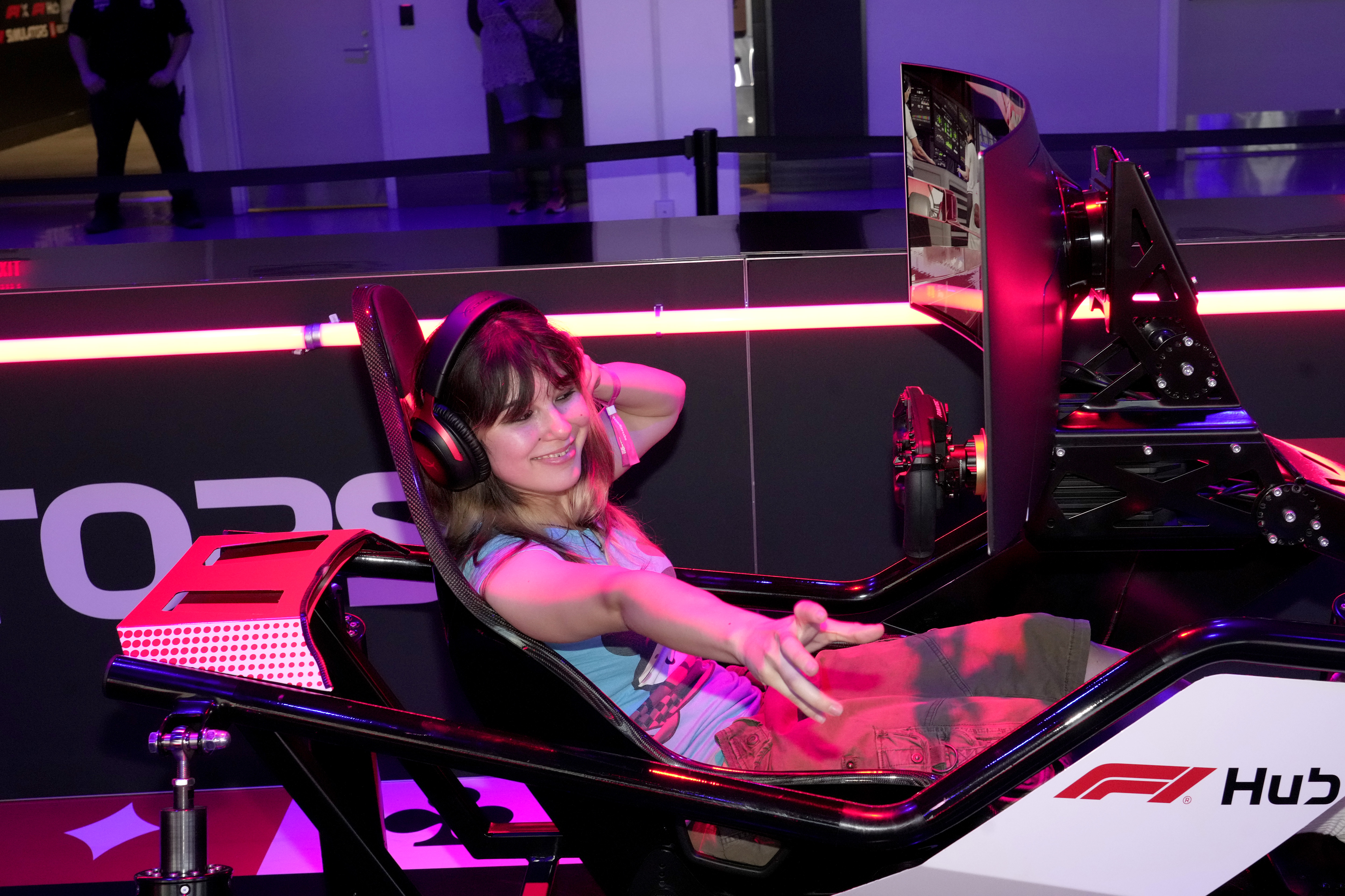 Alysa Liu seated in an F1 simulator at the F1 Paddock at Grand Prix Plaza in Las Vegas during Flavor Flav's SheWeekend