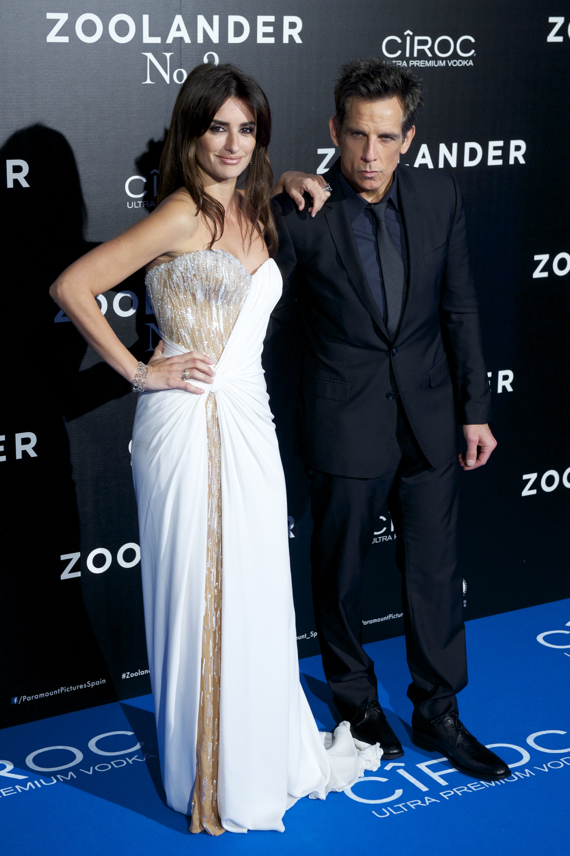 Click to open the image gallery Penelope Cruz in a white strapless gown and Ben Stiller in a black suit pose together in front of a Zoolander No. 2 step-and-repeat backdrop.