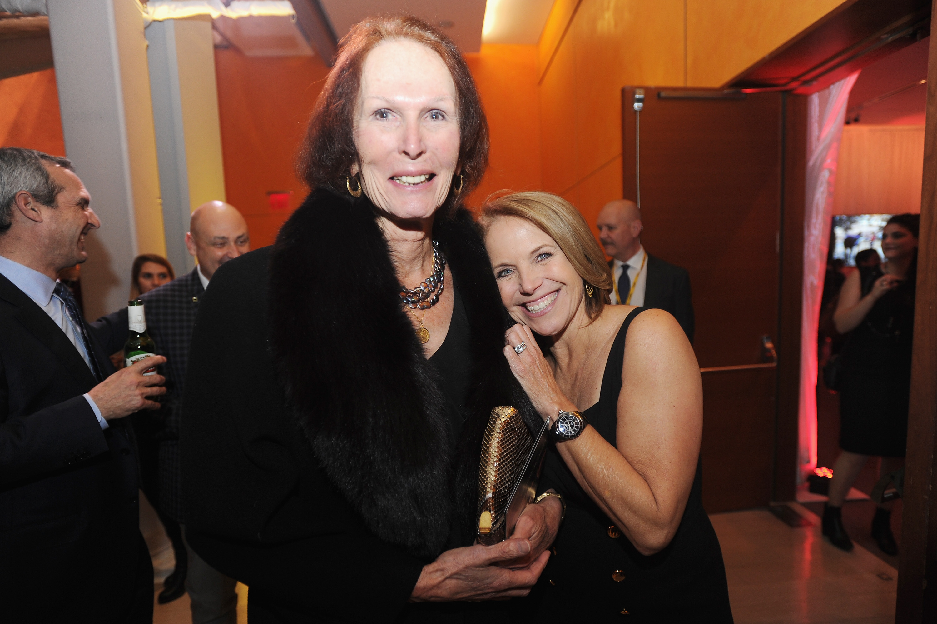 Renée Richards and Katie Couric smiling together at an indoor event, both dressed in black.