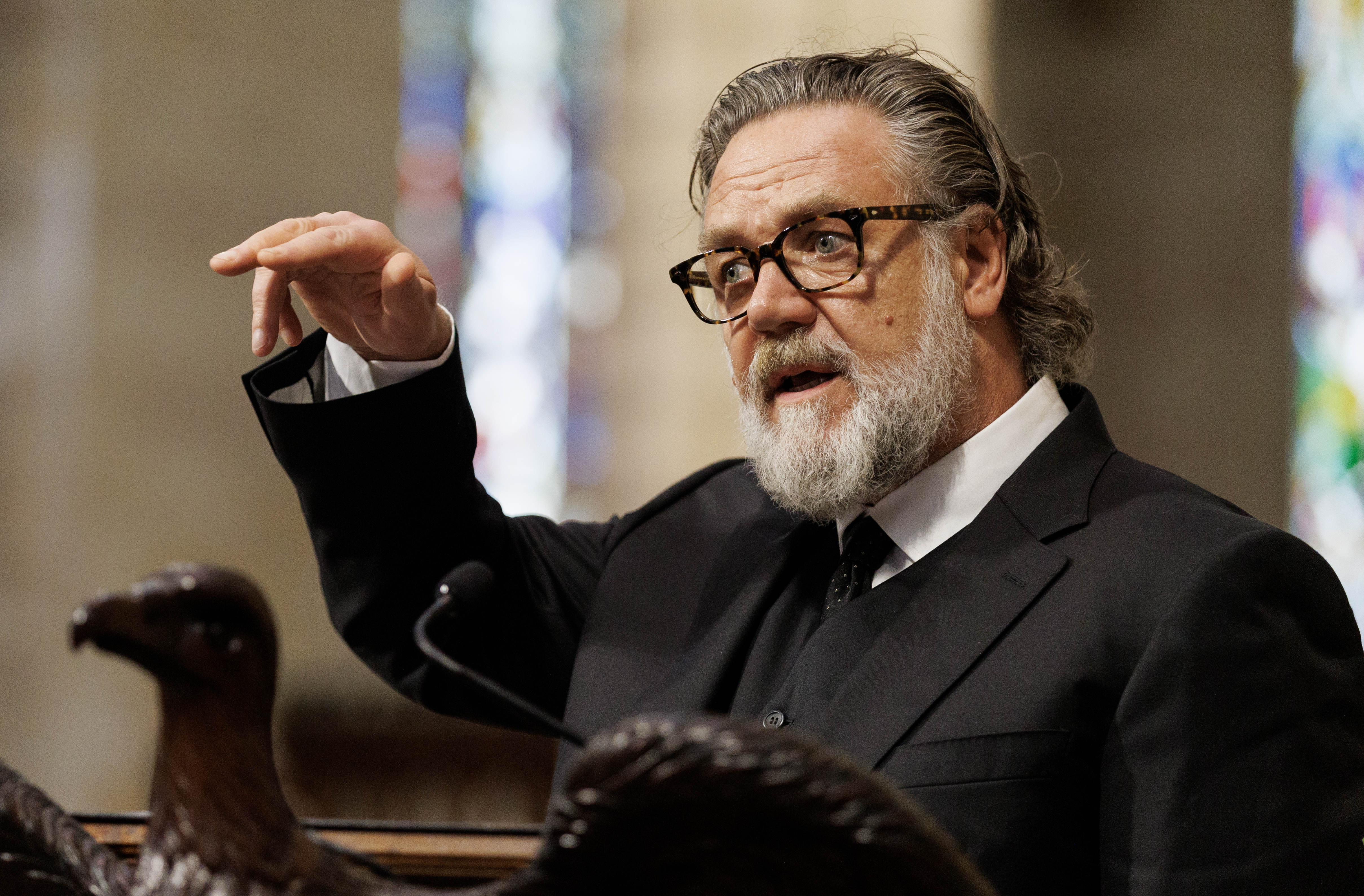 Russell Crowe speaking at a podium inside St. Andrew's Cathedral in Sydney at John Laws' state funeral