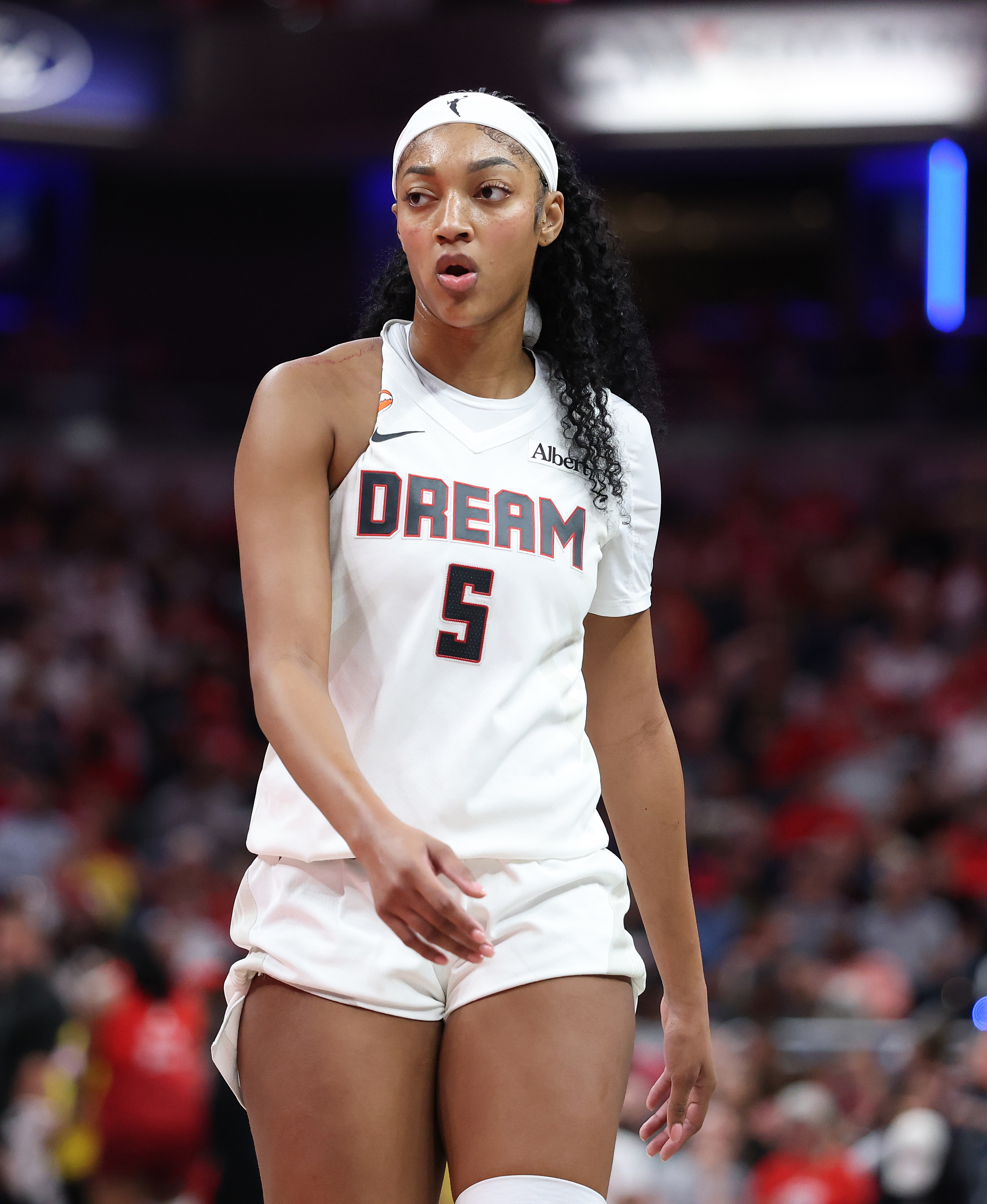 Angel Reese wearing Atlanta Dream jersey number 5 and a white headband stands on the court during a game.