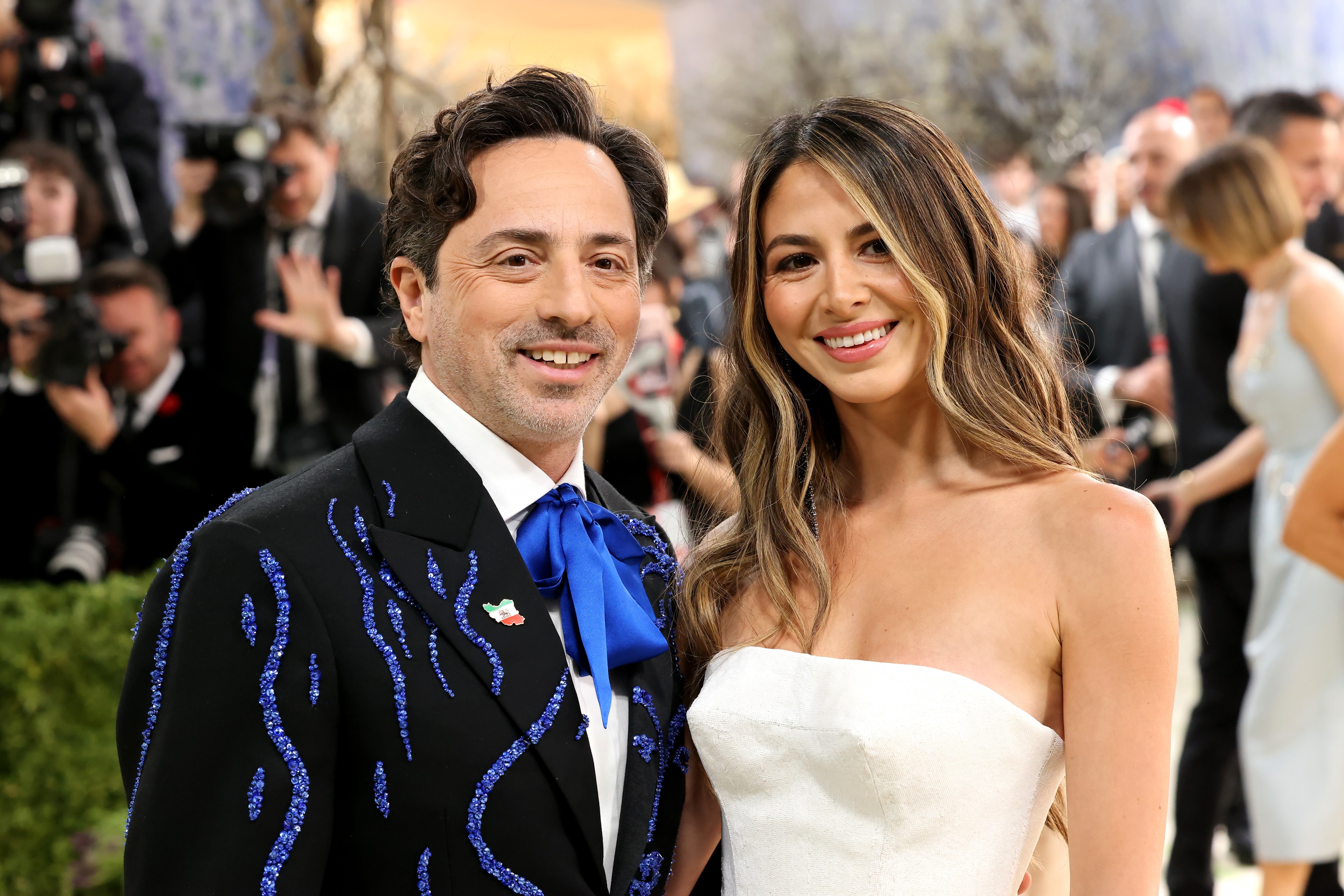 Sergey Brin in a black jacket with blue embroidery and a blue bow tie poses with Gerelyn Gilbert-Soto in a white strapless dress at the 2026 Met Gala.