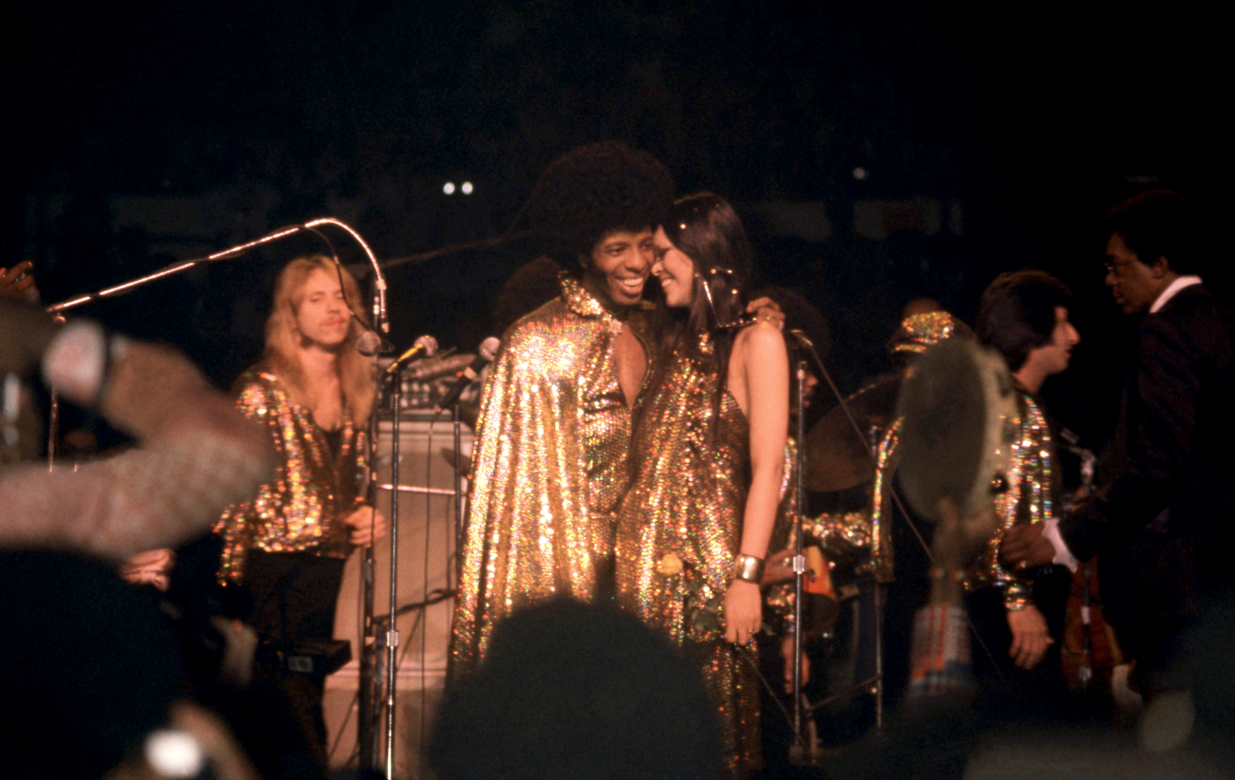 Click to open the image gallery Sly Stone and Kathy Silva smiling at their wedding at Madison Square Garden in 1974, with Don Cornelius standing at far right
