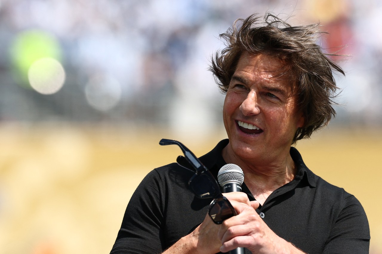 Tom Cruise speaking at a podium on the field at the 2026 World Cup final between Spain and Argentina