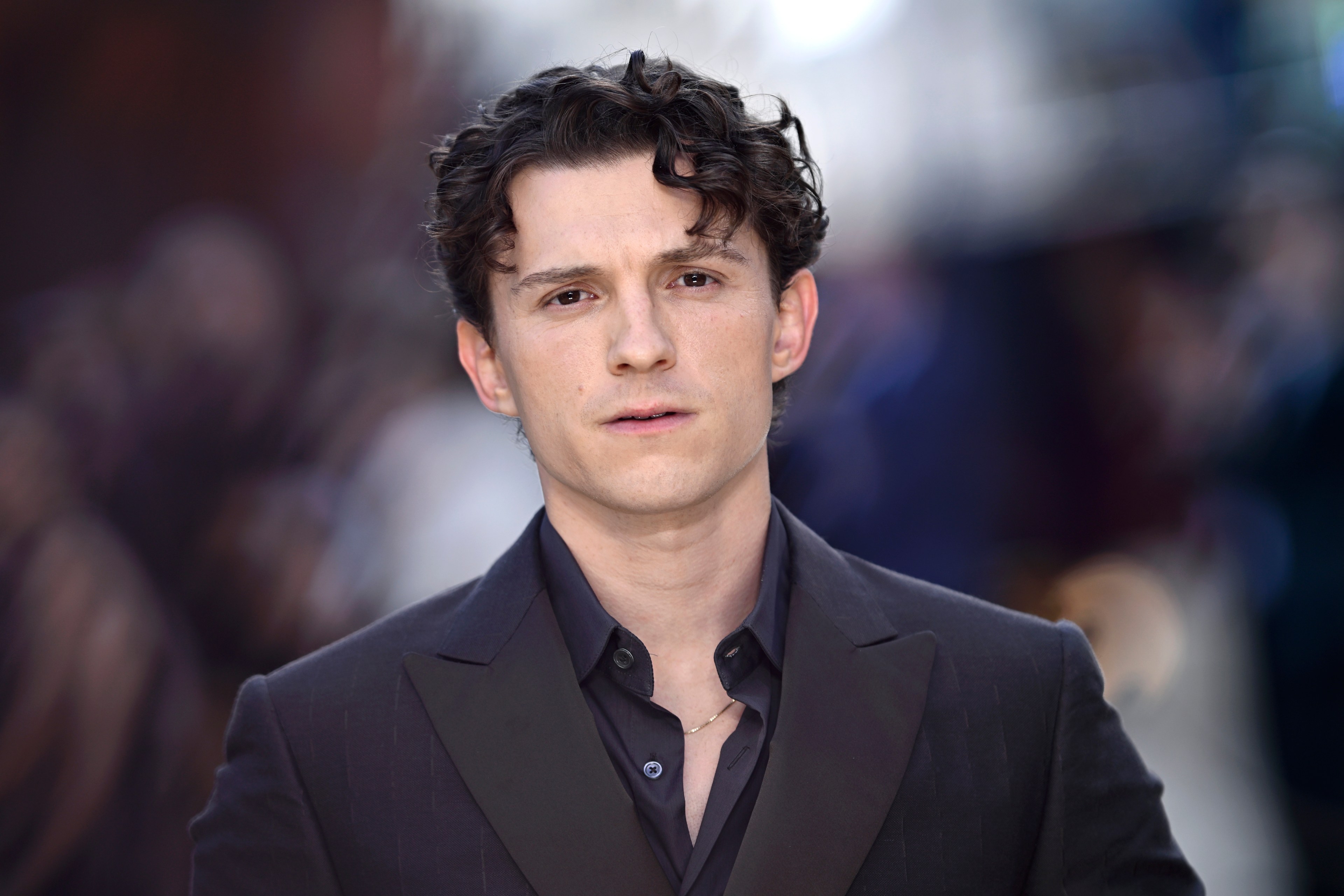 Tom Holland in a dark suit and open-collar shirt at the world premiere of The Odyssey in London.