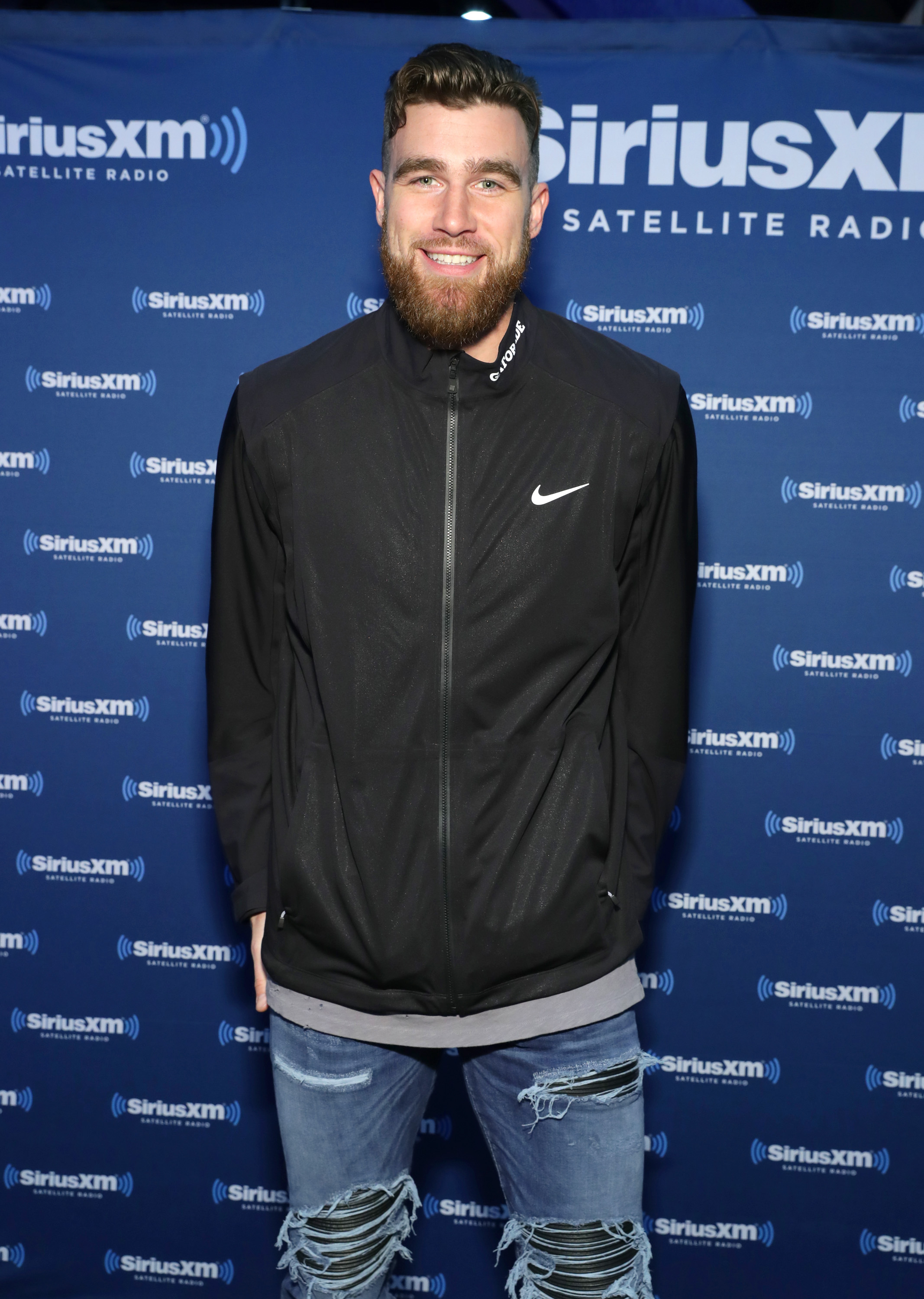 Travis Kelce sitting at the SiriusXM Radio Row set at the George R. Brown Convention Center during Super Bowl LI week