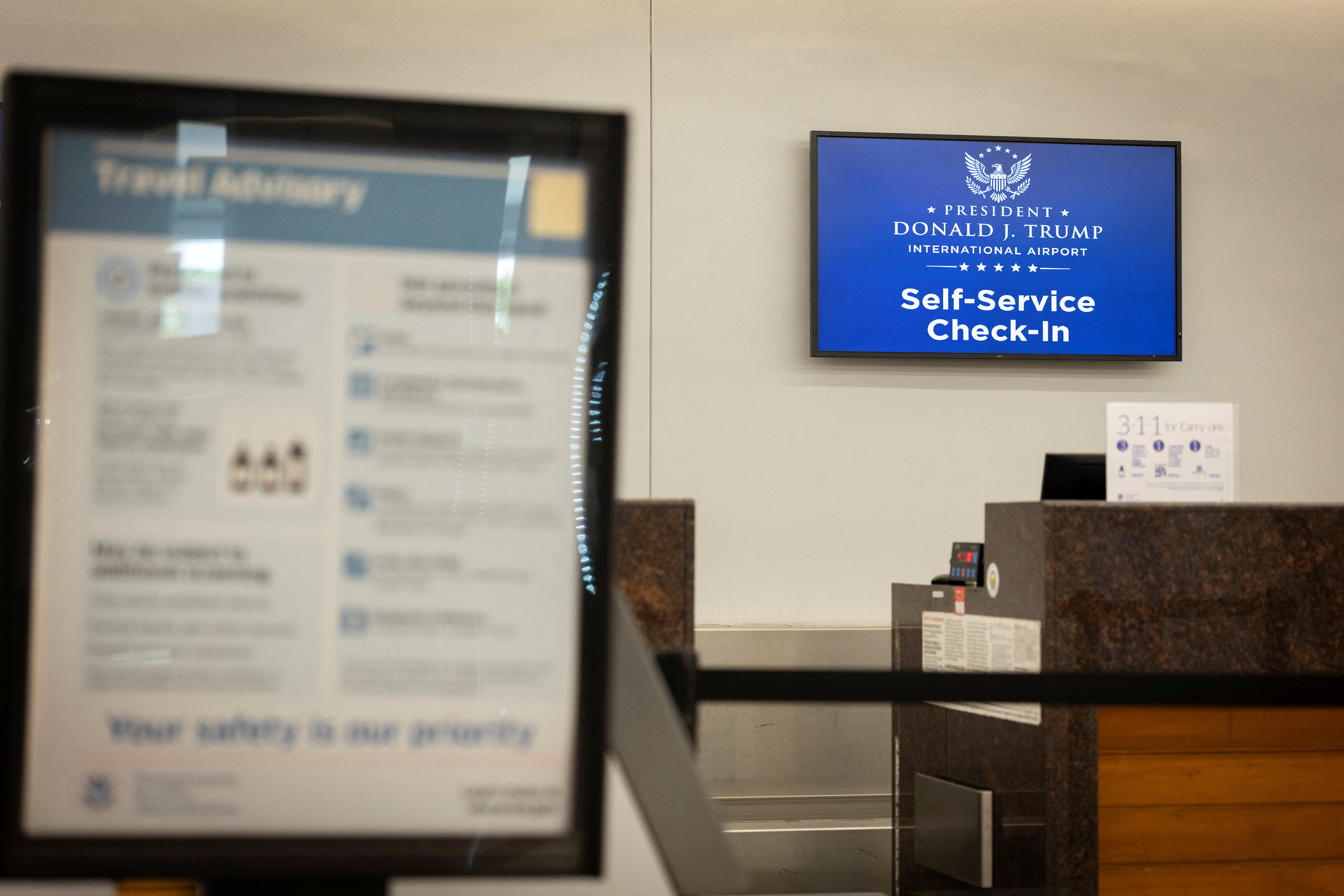 Airport information screen showing the renamed President Donald J. Trump International Airport at Palm Beach International Airport