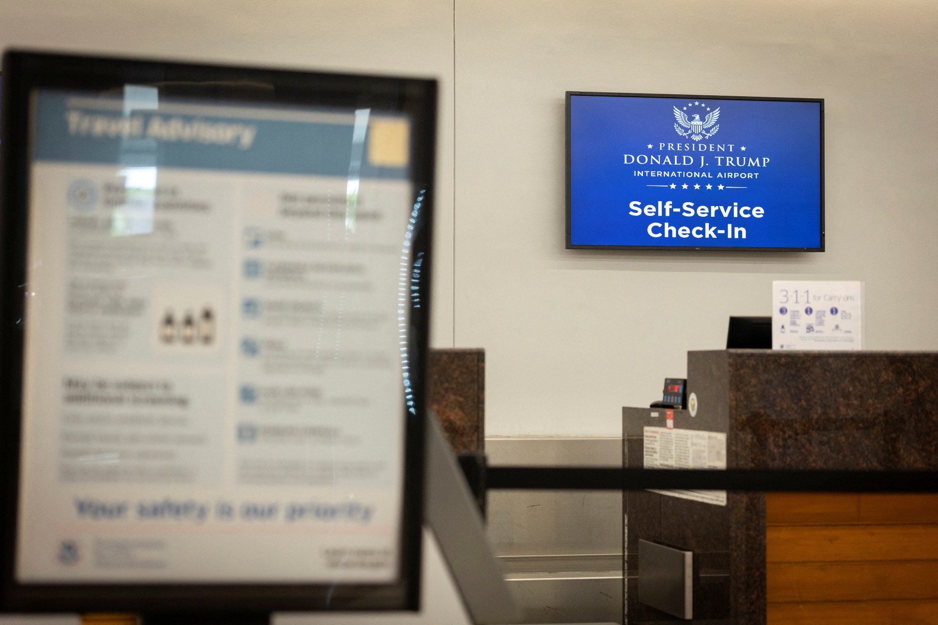 Airport information screen showing the renamed President Donald J. Trump International Airport at Palm Beach International Airport