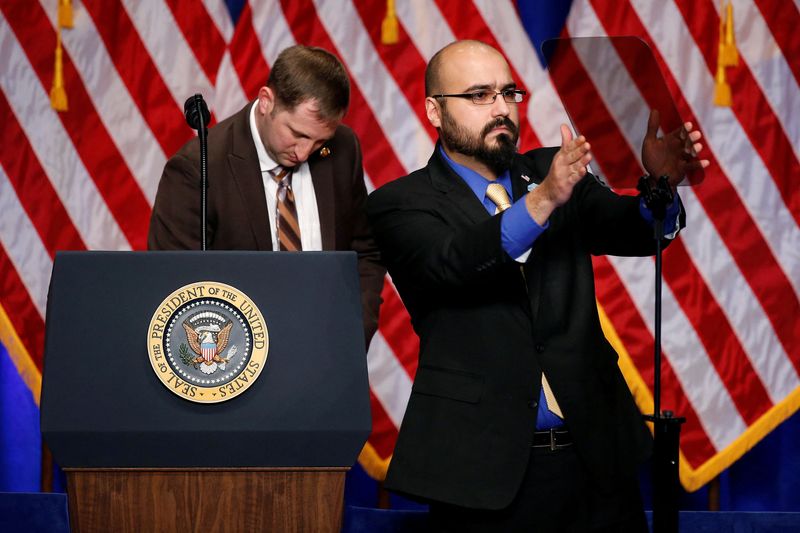 A technician adjusts a teleprompter on stage before a presidential speech at the Ronald Reagan Building in Washington, D.C.