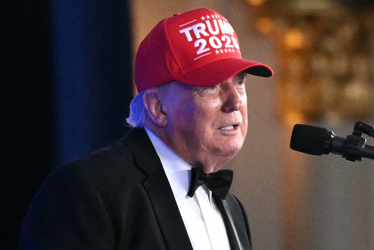 President Donald Trump in a "Trump 2028" hat speaking at the 2026 White House Correspondents' Dinner at the Waldorf Astoria in Washington, DC