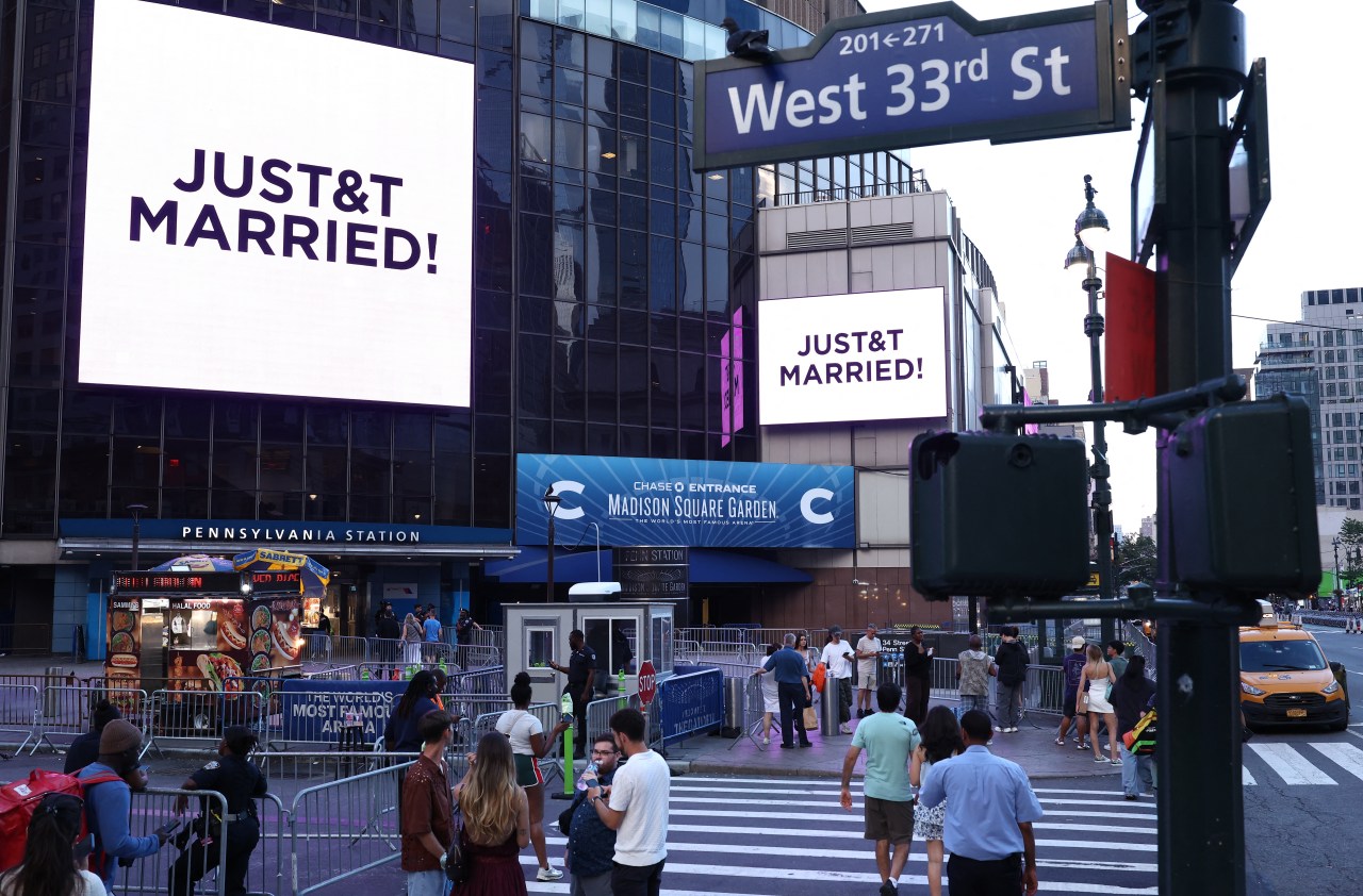 Giant screens outside Madison Square Garden displaying "JUST&T MARRIED!" for Taylor Swift and Travis Kelce's wedding celebration