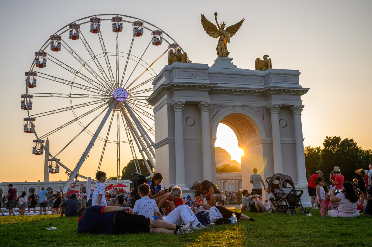 People lying on grass near a Ferris wheel at the Great American State Fair in Washington, D.C.