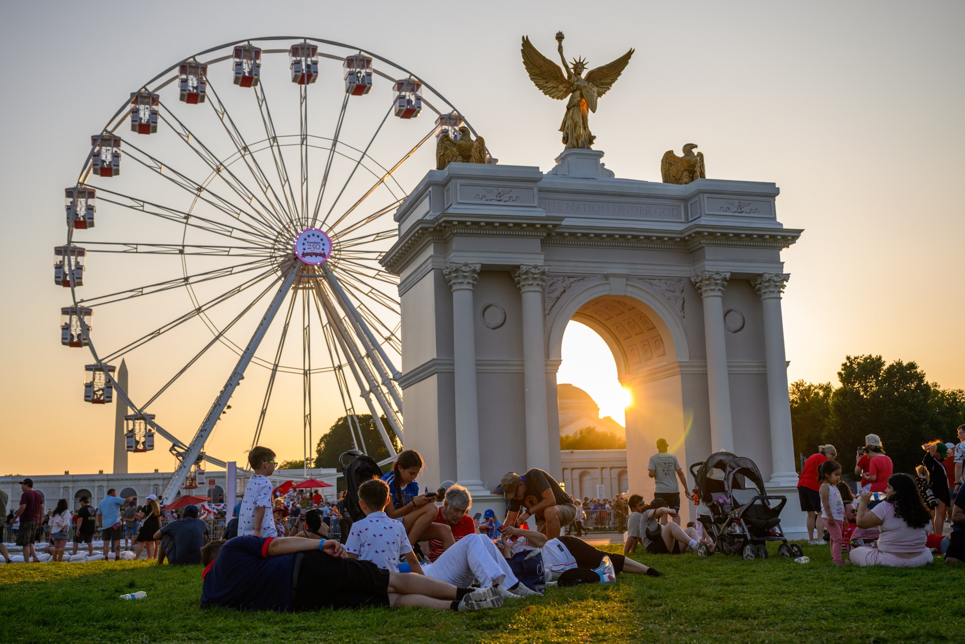 People lying on grass near a Ferris wheel at the Great American State Fair in Washington, D.C.