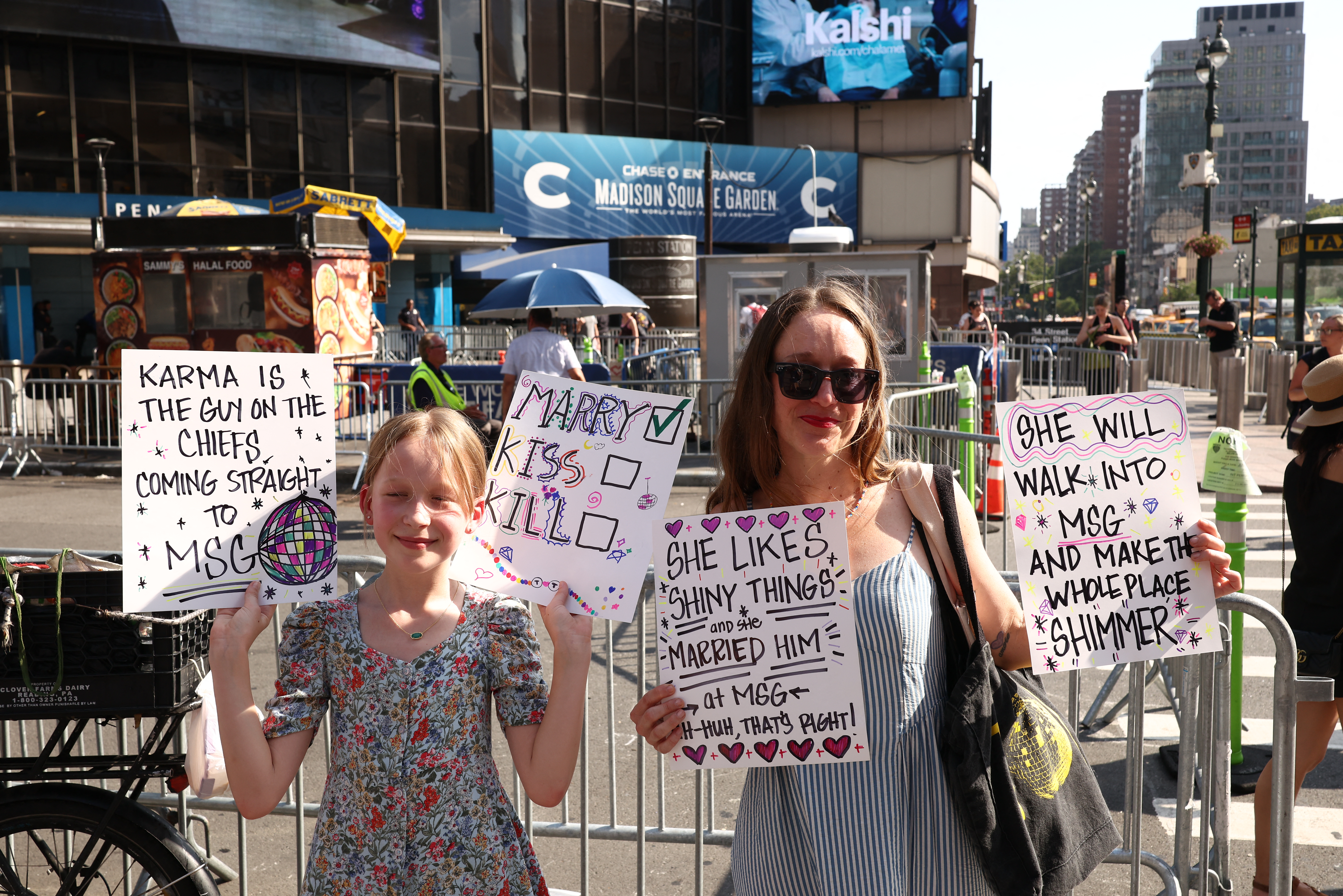 Taylor Swift fans holding signs outside Madison Square Garden in New York City ahead of the reported Swift-Kelce wedding celebrations