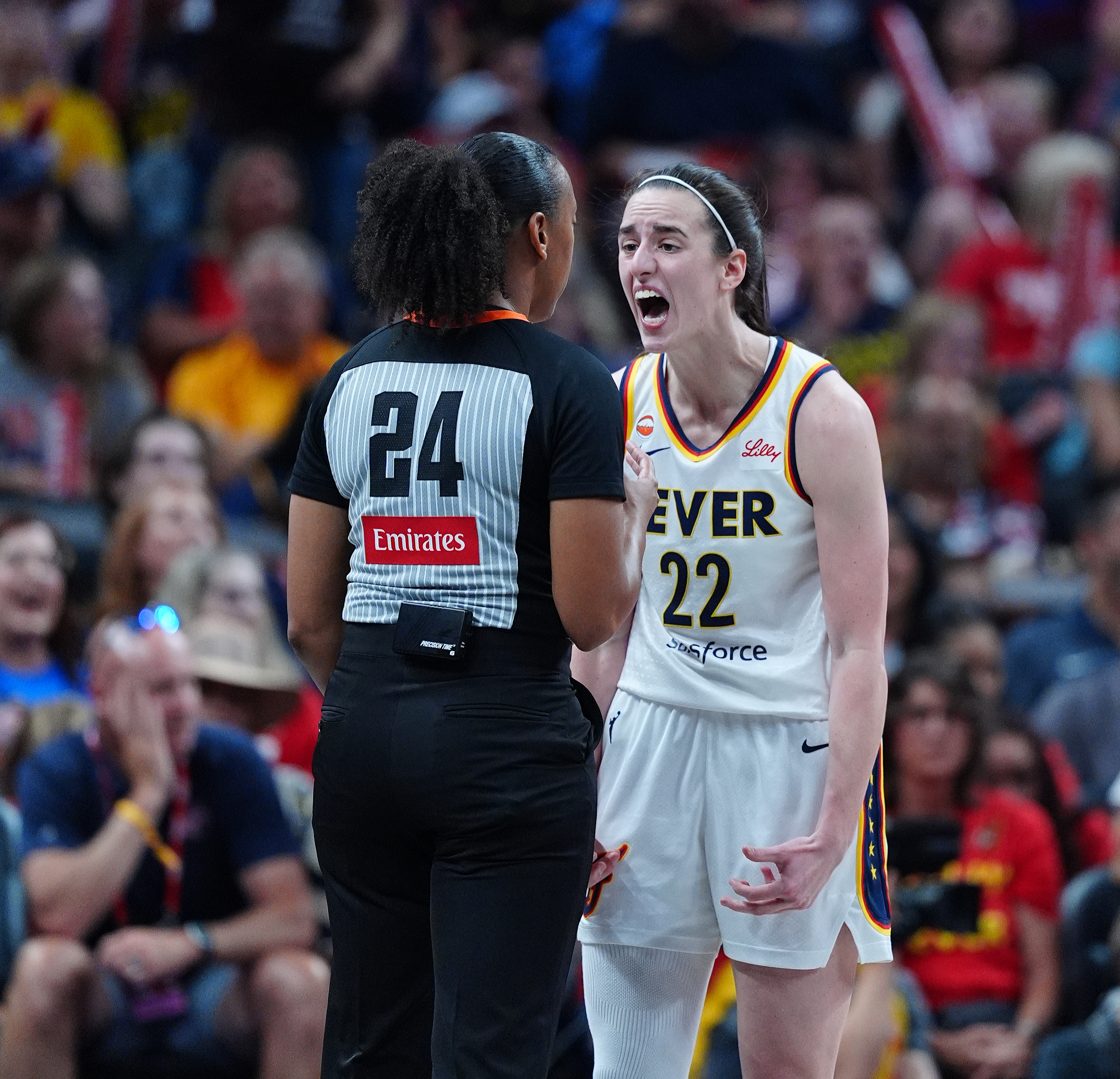 Indiana Fever guard Caitlin Clark (#22) shouts at a referee wearing number 24 during a WNBA game at Gainbridge Fieldhouse.