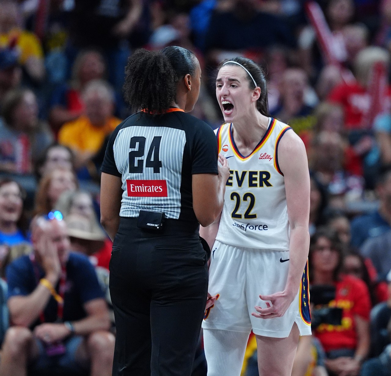 Indiana Fever guard Caitlin Clark (#22) shouts at a referee wearing number 24 during a WNBA game at Gainbridge Fieldhouse.