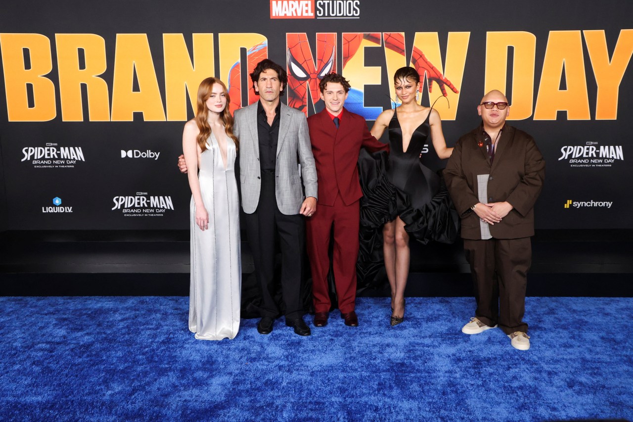 Five cast members pose together on a blue carpet in front of a Spider-Man: Brand New Day premiere backdrop at Marvel Studios event.