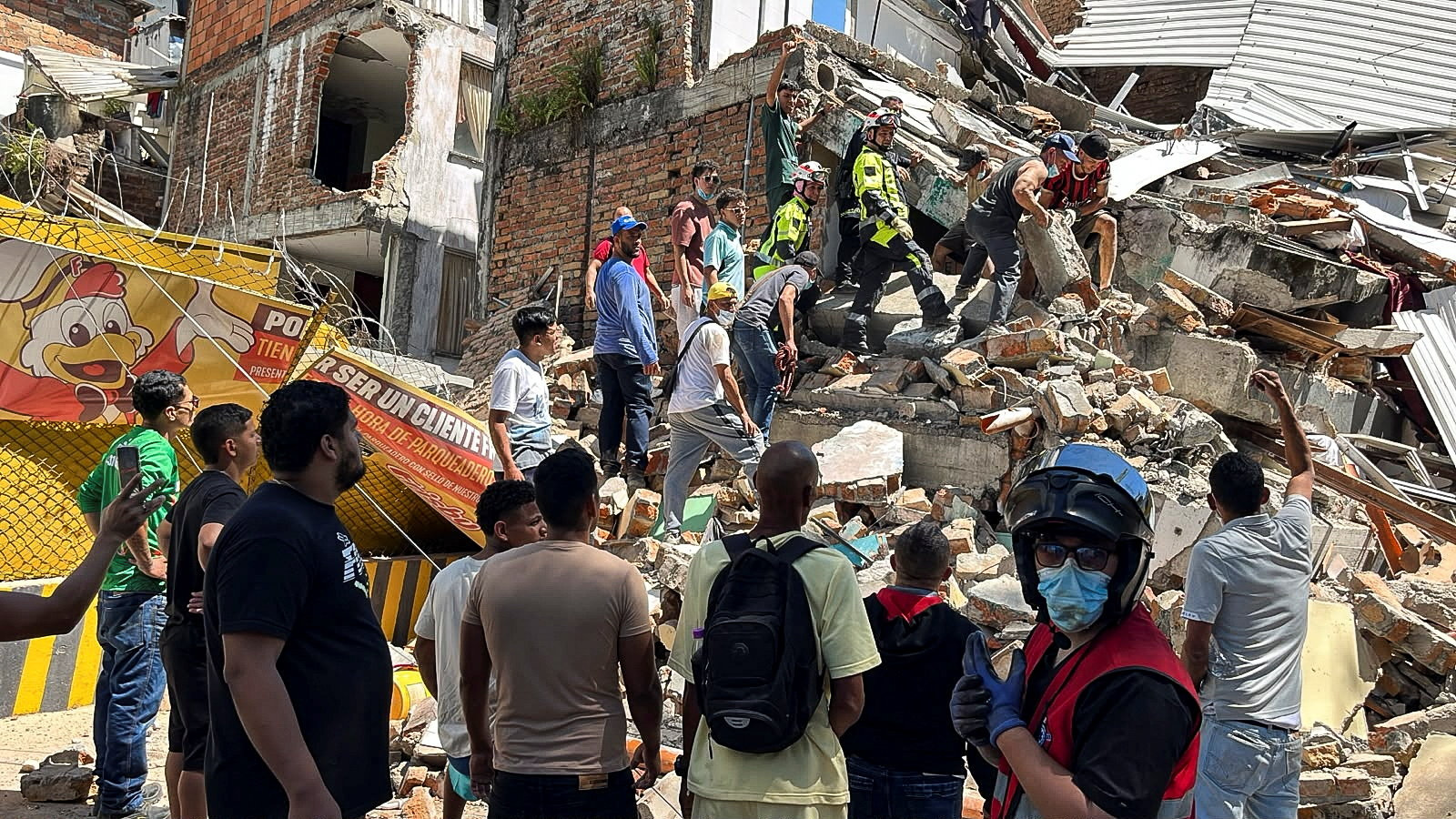 Rescue workers and residents digging through debris of a partially collapsed building in Pereira, Colombia after an earthquake