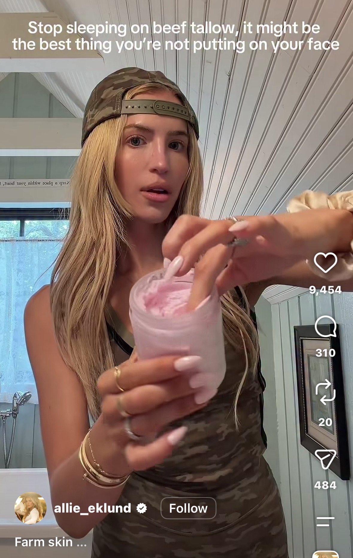 Blonde woman in camo headband holds an open jar of pink whipped cream product toward the camera while standing in a bathroom.