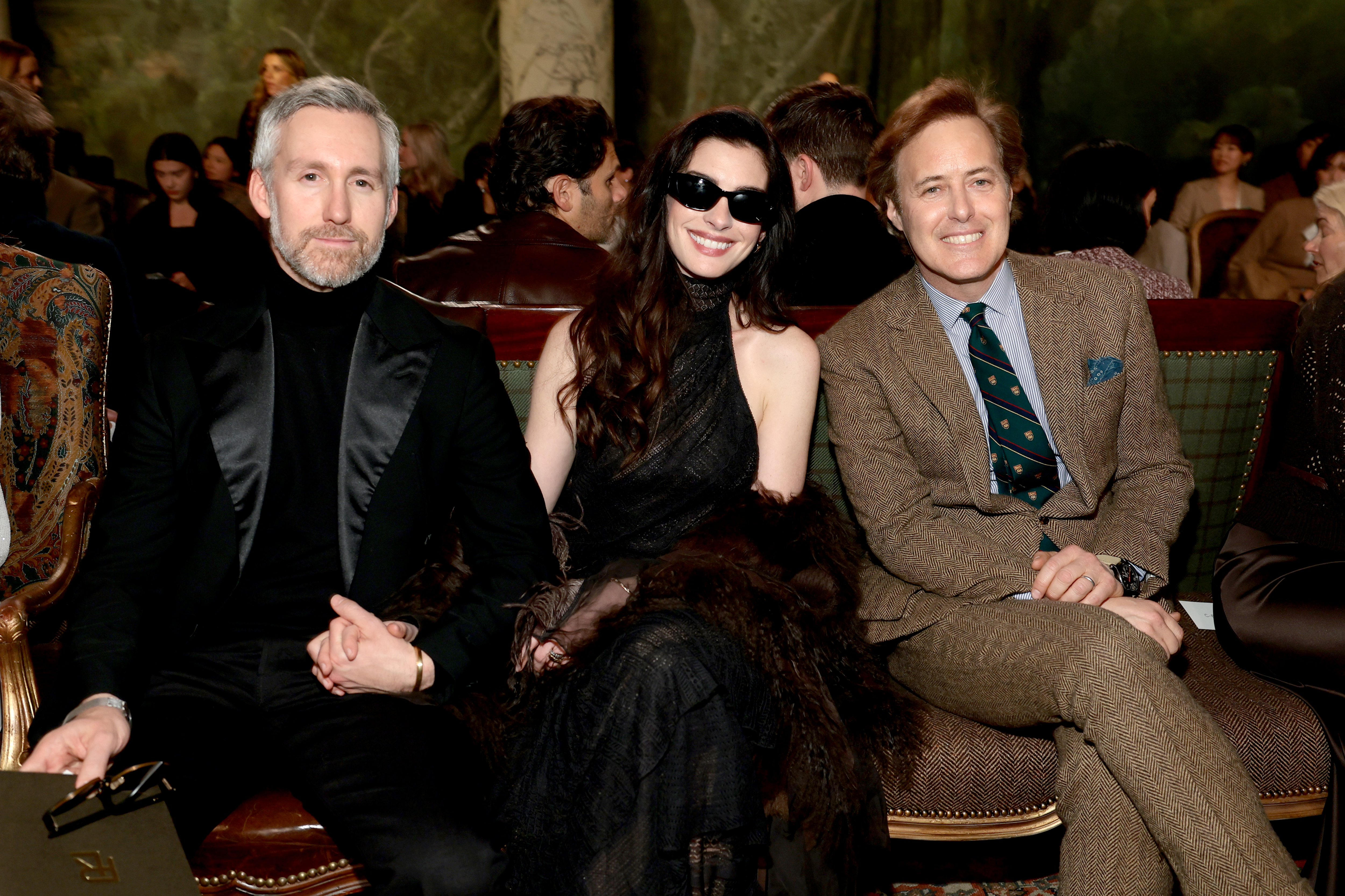 Adam Shulman, Anne Hathaway, and David Lauren sitting front row at the Ralph Lauren fashion show during New York Fashion Week