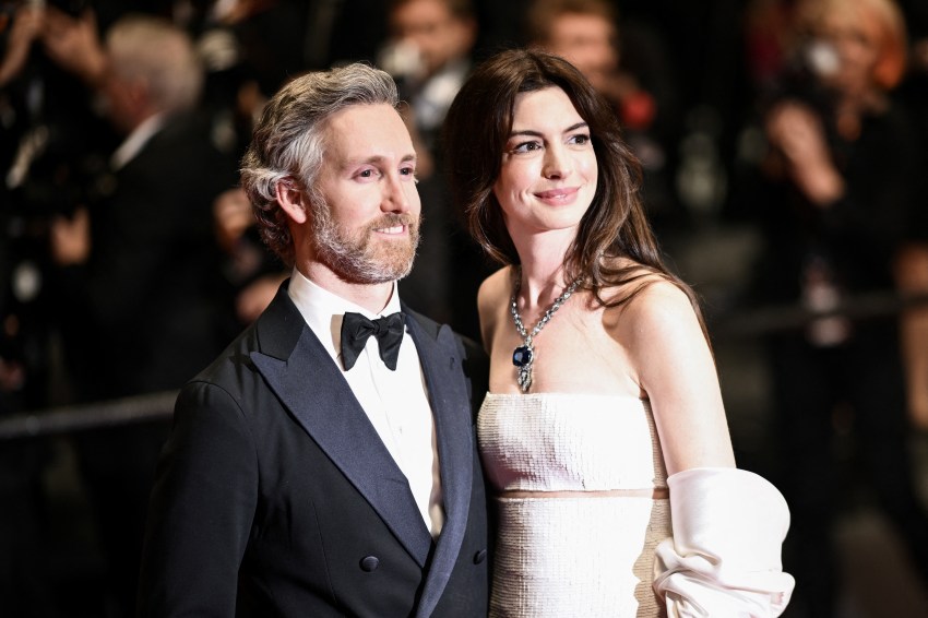 Anne Hathaway in a white strapless gown and Adam Shulman in a black tuxedo posing together at the Cannes Film Festival.