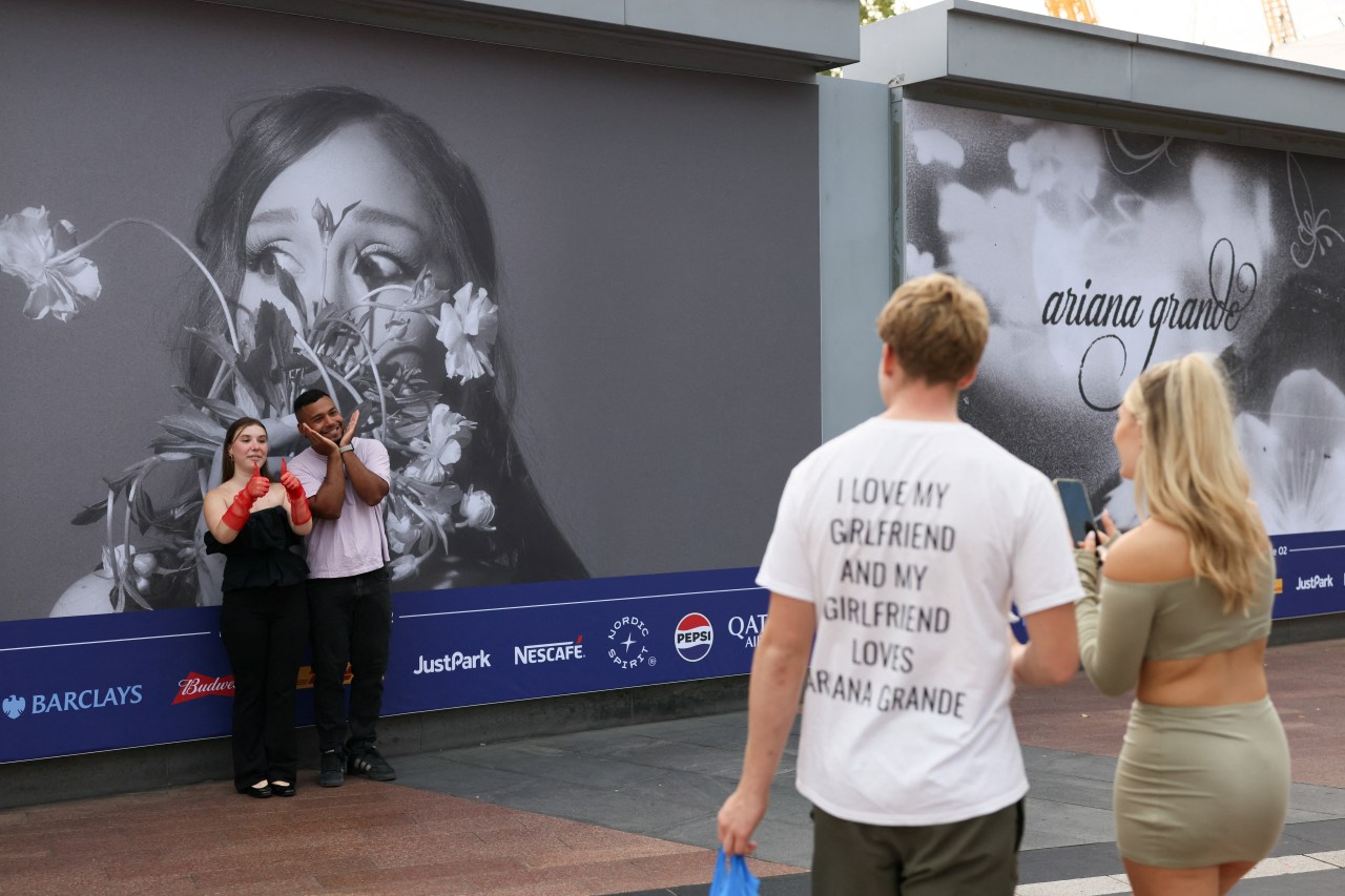 Ariana Grande fans taking pictures in front of a billboard before the opening night of The Eternal Sunshine Tour in London