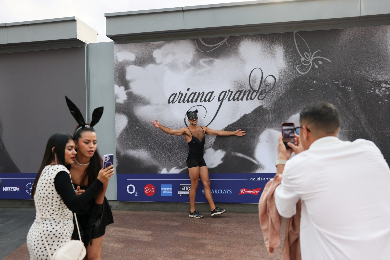 An Ariana Grande fan photographing a billboard ahead of The Eternal Sunshine Tour's London opening night