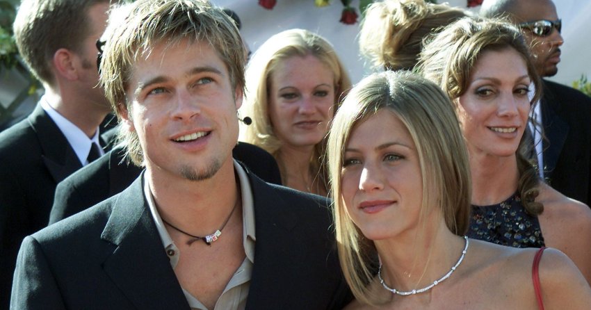 A man and woman posing together at a red carpet event, surrounded by a crowd of attendees outdoors.