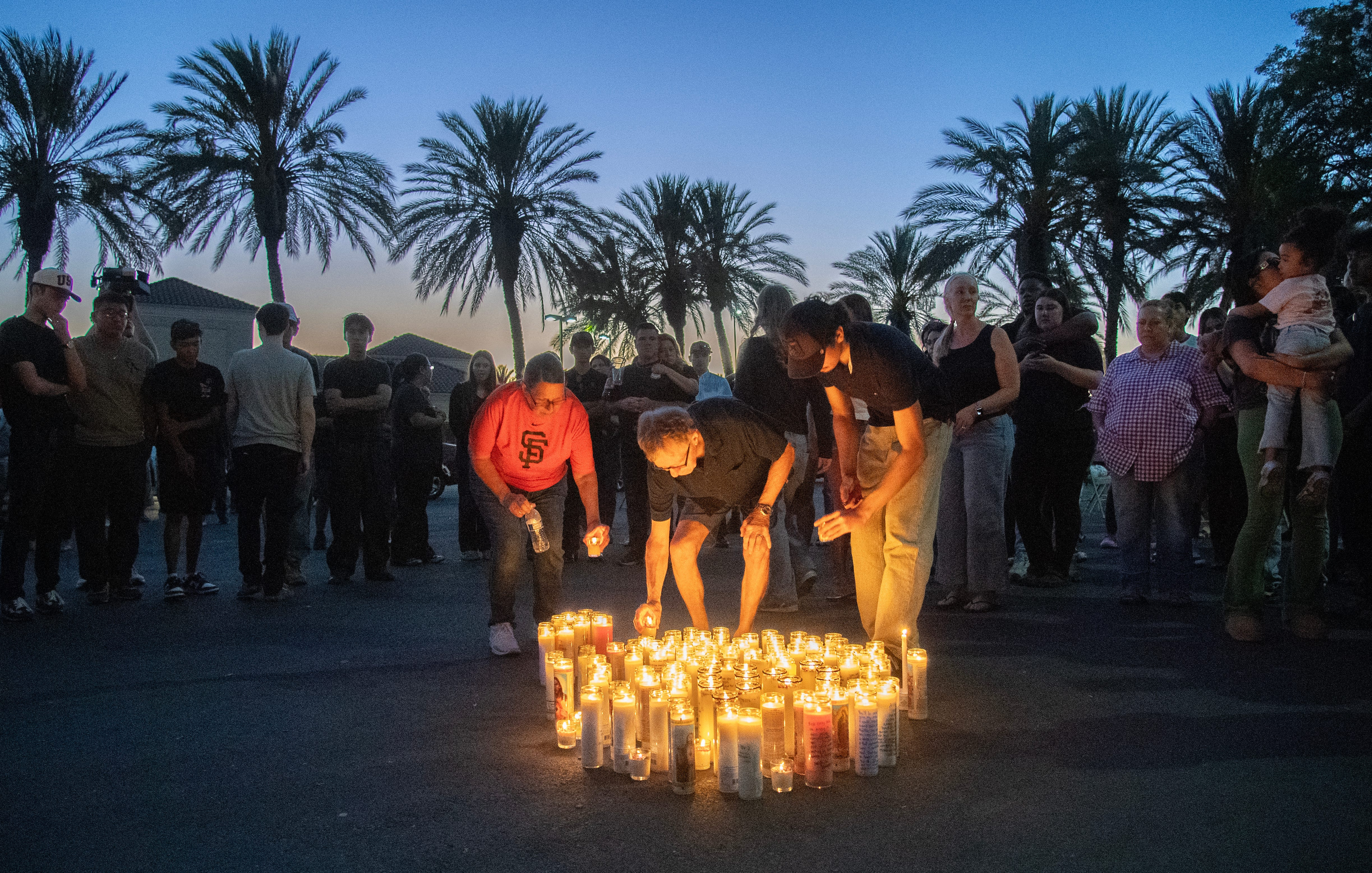 People holding lit candles in a vigil at an In-N-Out Burger parking lot in Stockton, honoring shooting victim Ashely Garibay