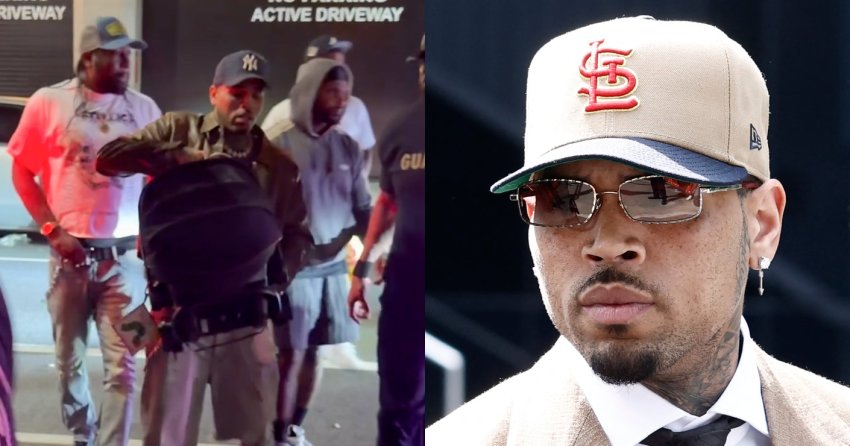 Chris Brown wearing a NY Yankees cap and baby carrier walks through a NYC driveway entrance at night, surrounded by several men.