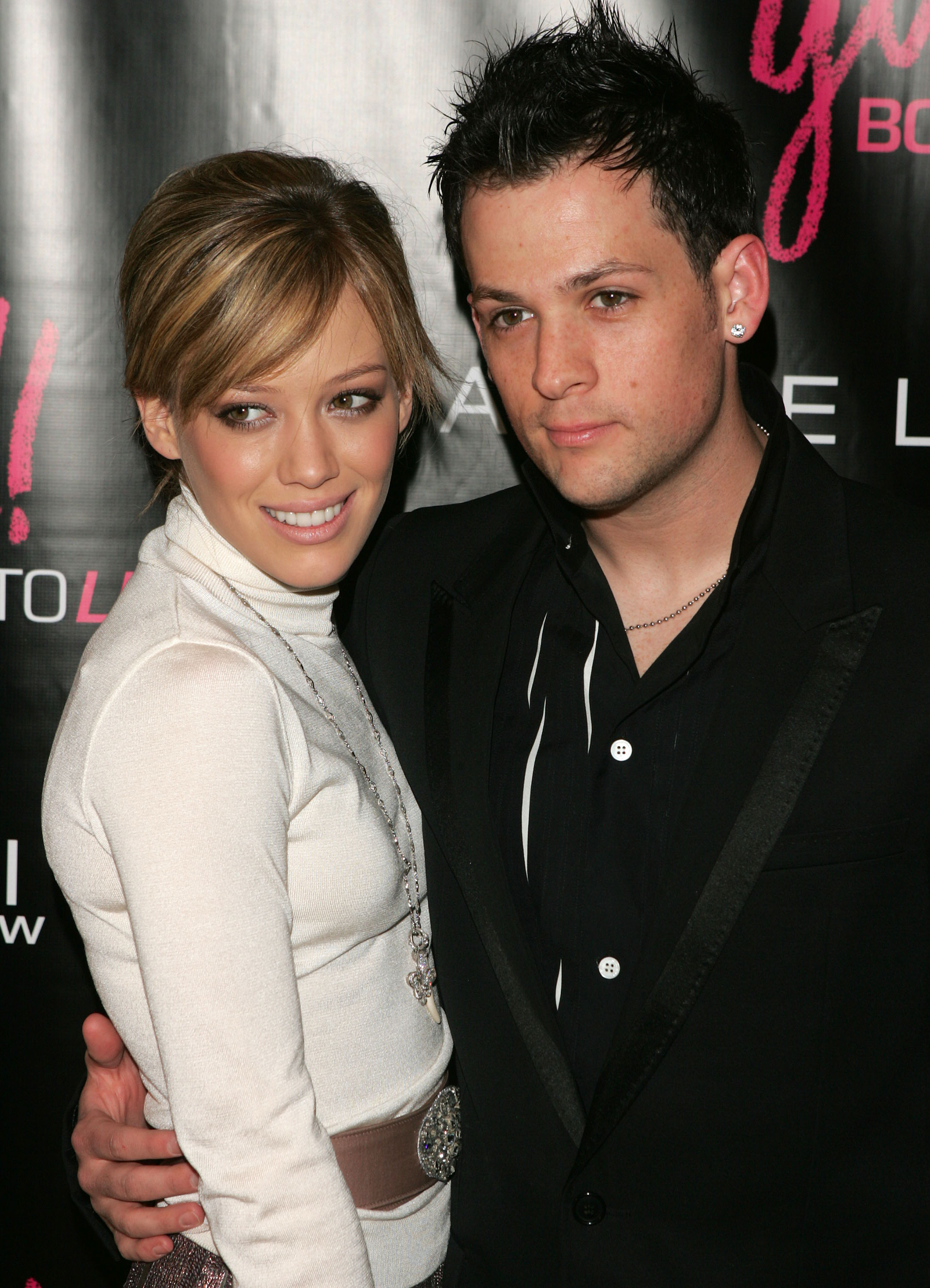 Hilary Duff in a white turtleneck and Joel Madden in a black jacket pose together at a CosmoGirl event in 2005.