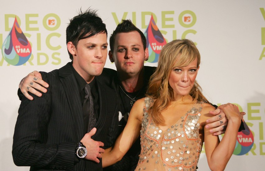 Joel Madden, Benji Madden, and Hilary Duff posing together at the 2005 MTV VMAs press room in Miami, with the VMA backdrop behind them.