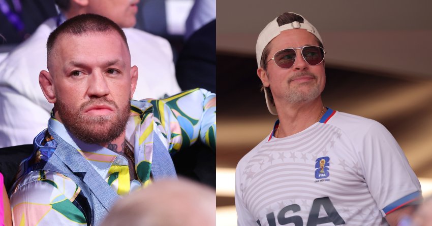 Conor McGregor seated ringside at Wembley Stadium, wearing a colorful patterned shirt over a blue jacket, with a serious expression.