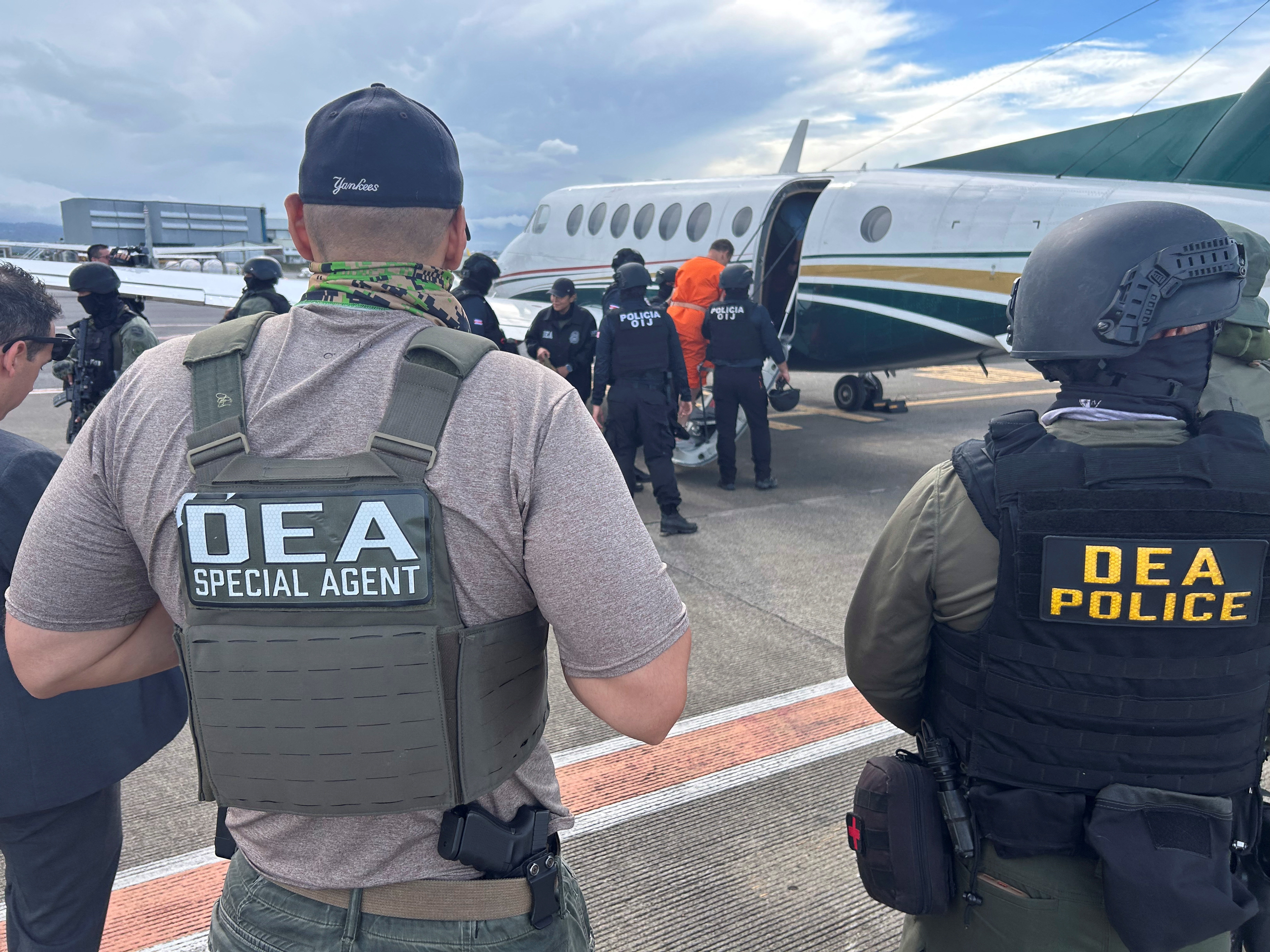 Security forces escort an alleged drug trafficker onto a plane at Juan Santamaría International Airport in Alajuela, Costa Rica
