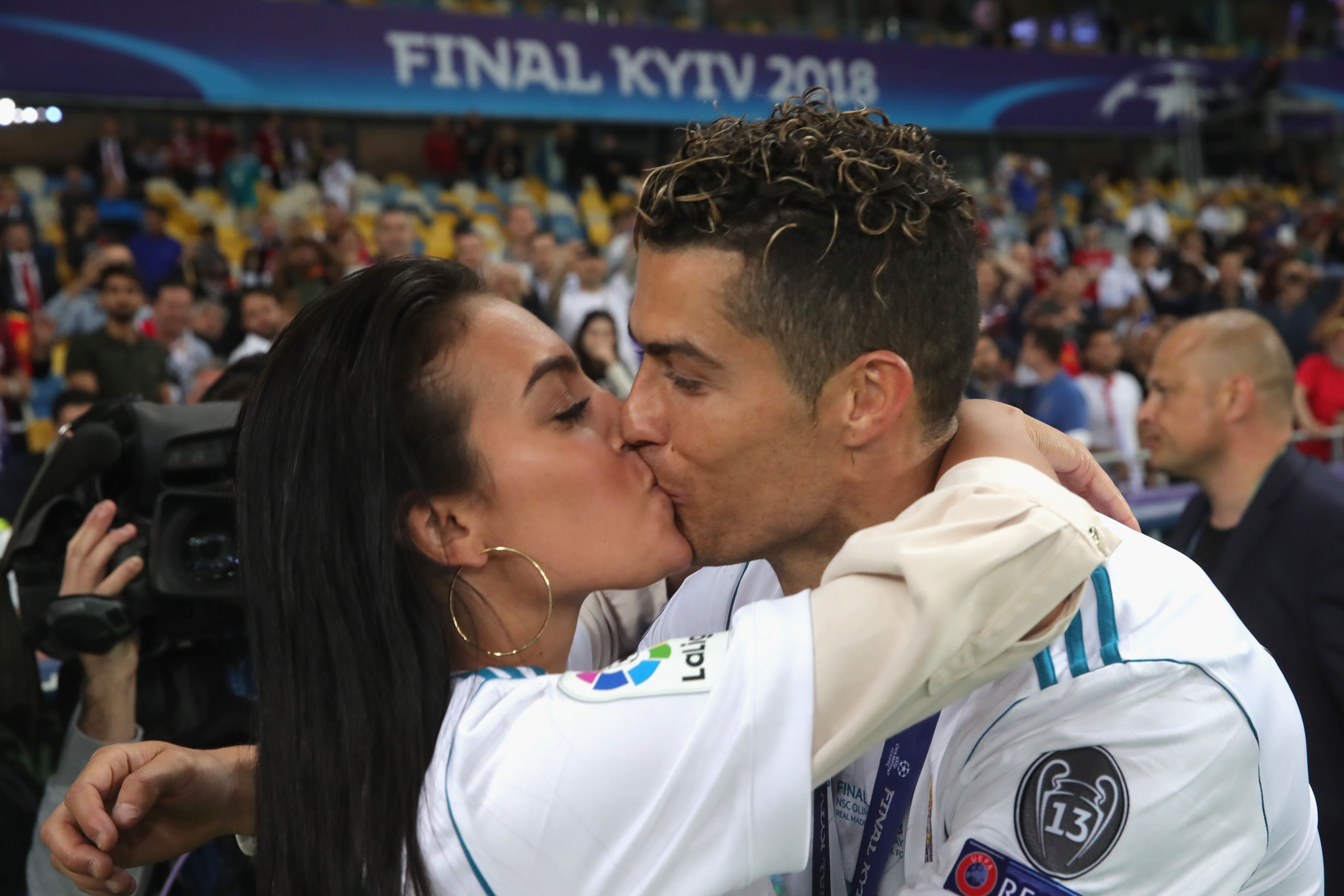 Cristiano Ronaldo in a Real Madrid jersey kisses Georgina Rodríguez on the field at the 2018 UEFA Champions League Final in Kyiv.