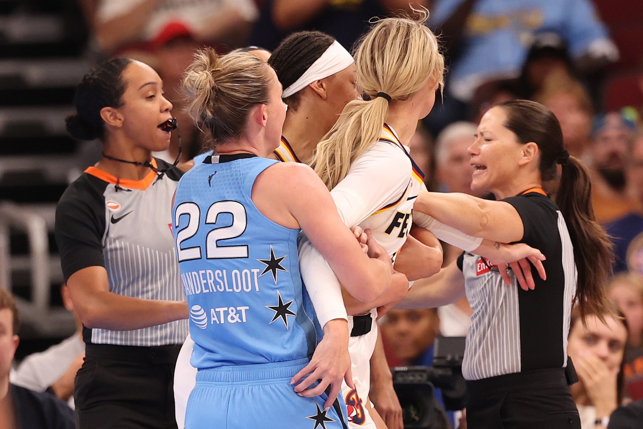 WNBA referees pull apart Chicago Sky's Carrington and Indiana Fever's Cunningham as the two players grab each other during a scuffle, with Chicago Sky's #22 Vandersloot nearby.