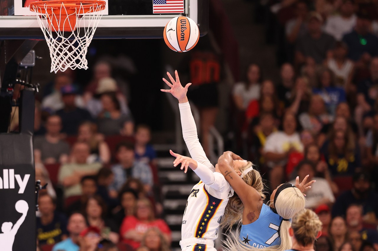 Indiana Fever player Sophie Cunningham reaches for a layup while being fouled by a Chicago Sky defender near the basket.